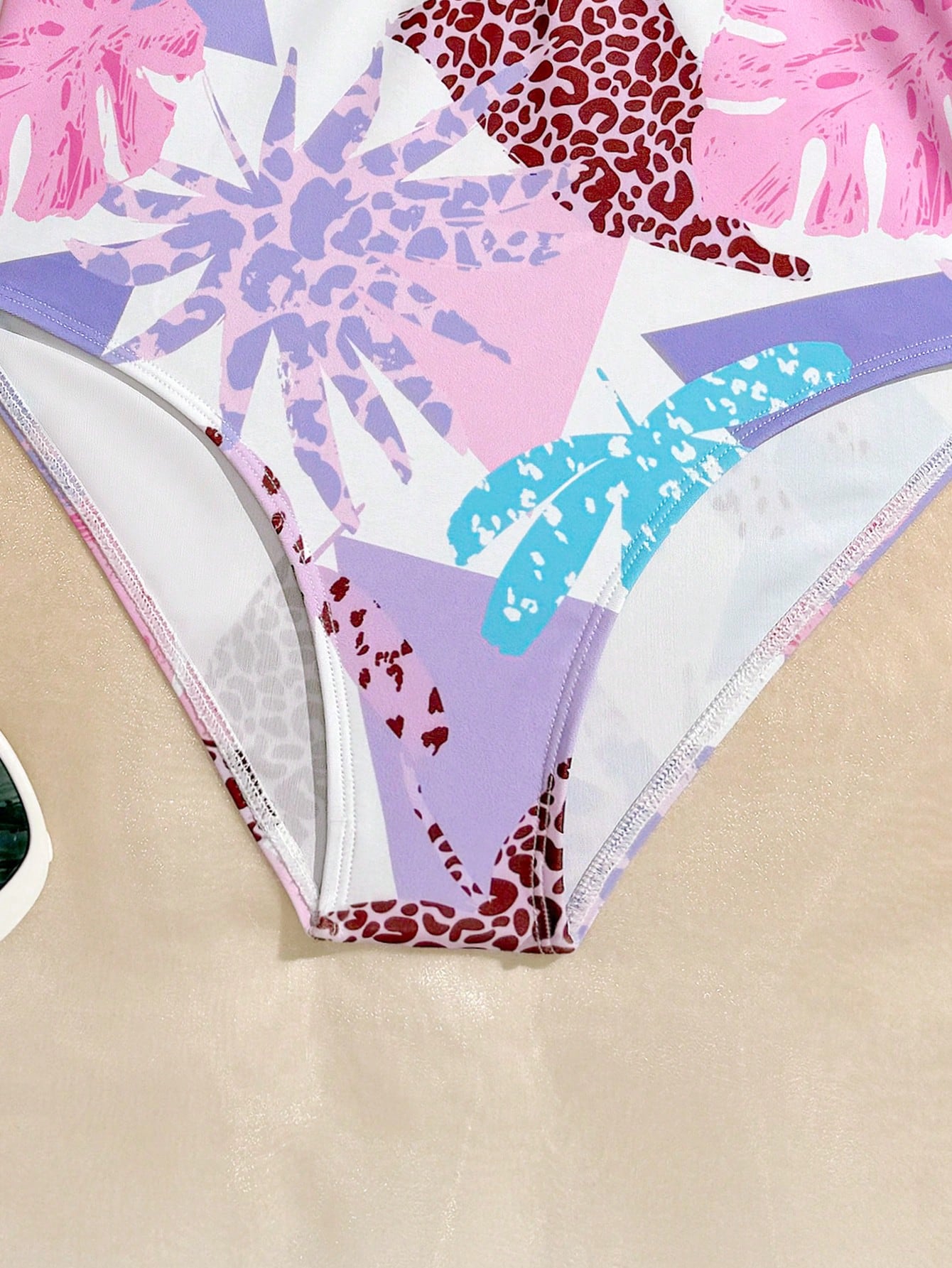 Girls one-piece swimsuit in blue with all-over leopard leaf print, ruffle detail, zipper front, high neck, and lined body for swimming and vacation.