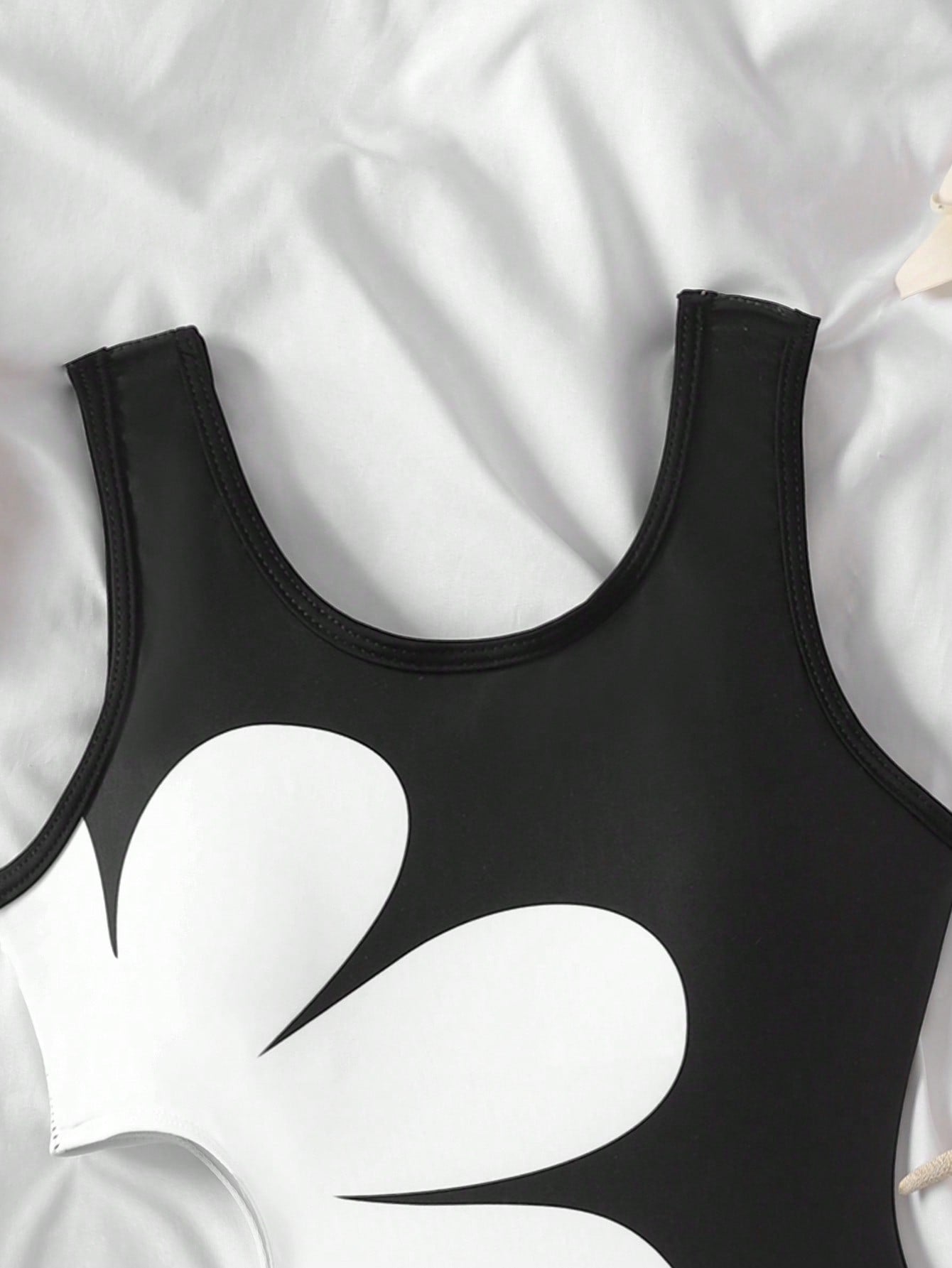Tween girls' black and white one-piece swimsuit with striped patchwork design, scoop neck, asymmetrical cut-out detail, and fitted vacation swimwear style.