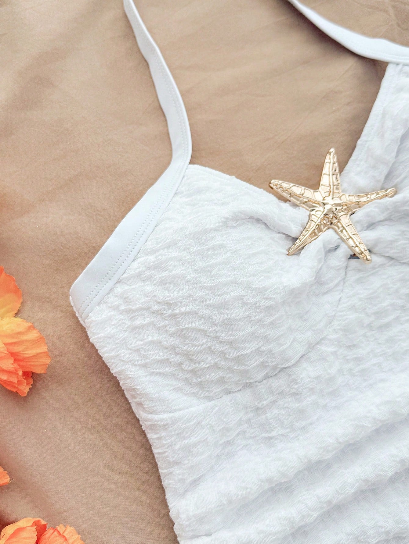 Pink textured halter one-piece swimsuit for tween girls with V-neck, tie strap, starfish and shell tassel accents, and lined body.