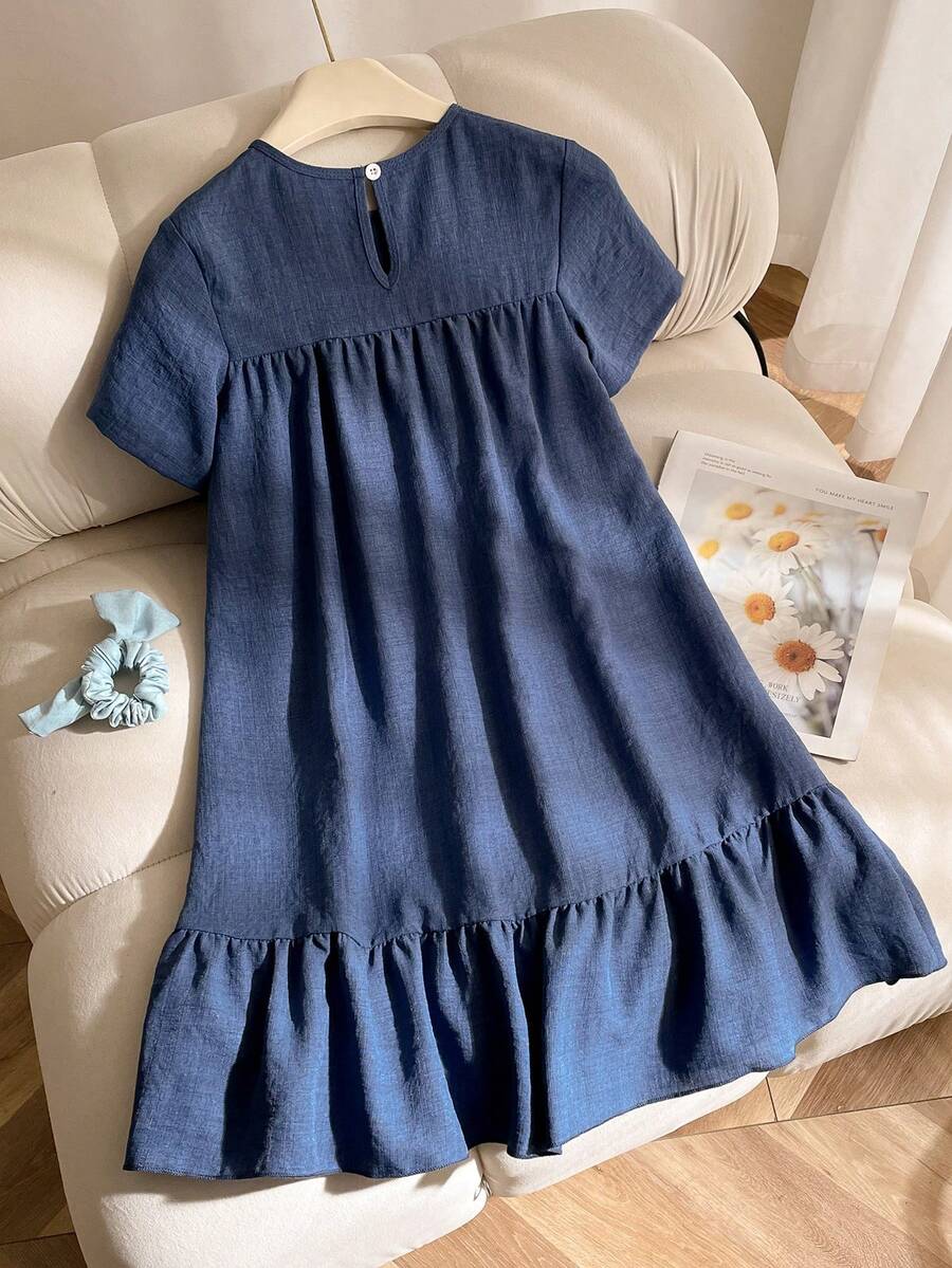 Tween girl wearing an Army Green textured short sleeve smock midi dress with round neck and ruffle flounce hem.