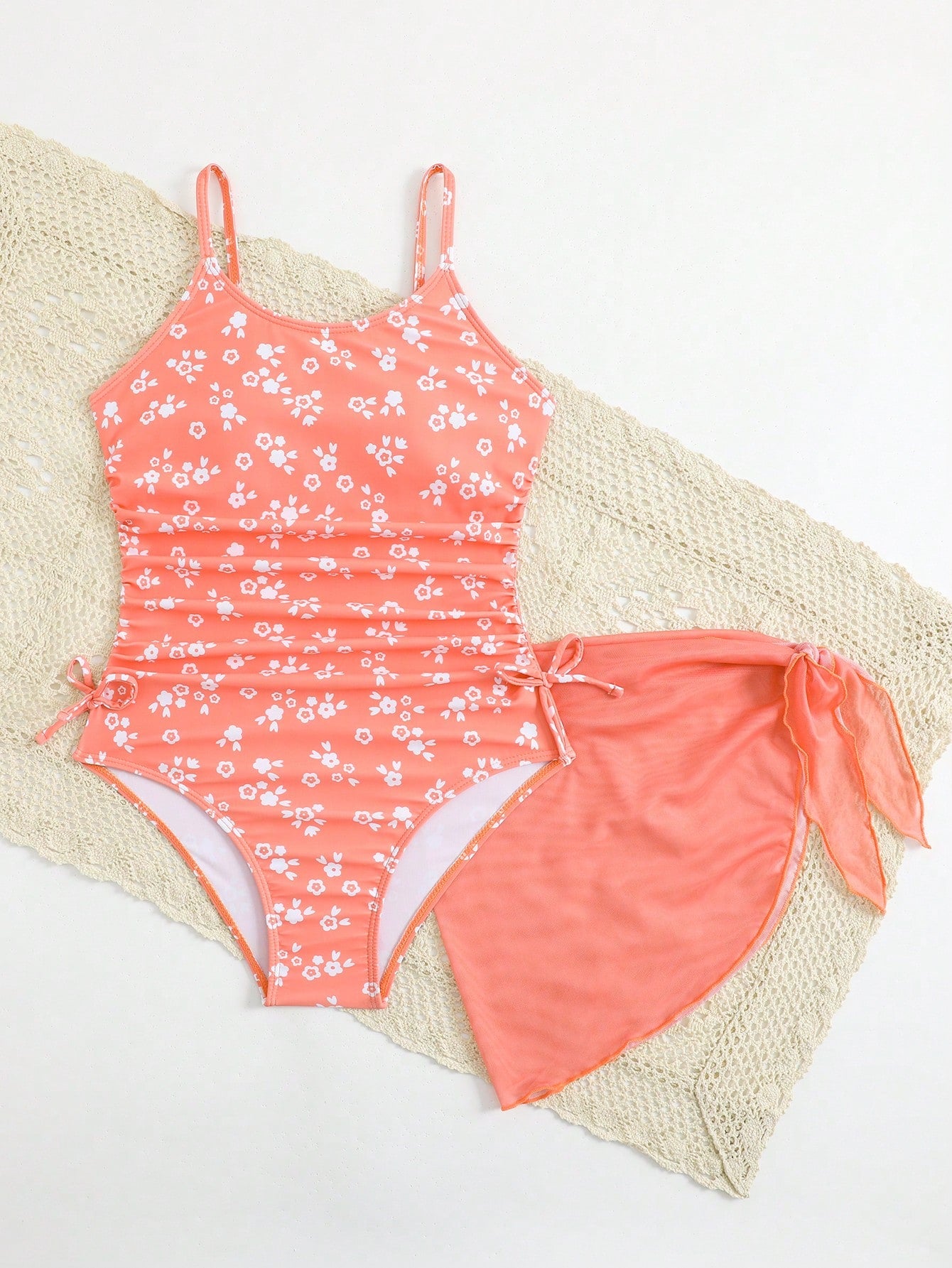 Tween girls 2-piece swimsuit in black with pink floral print, featuring spaghetti straps, bow decor, mesh detail, and a skirted mid-waist bottom. Sleeveless vacation-style swim set with medium-stretch fabric.