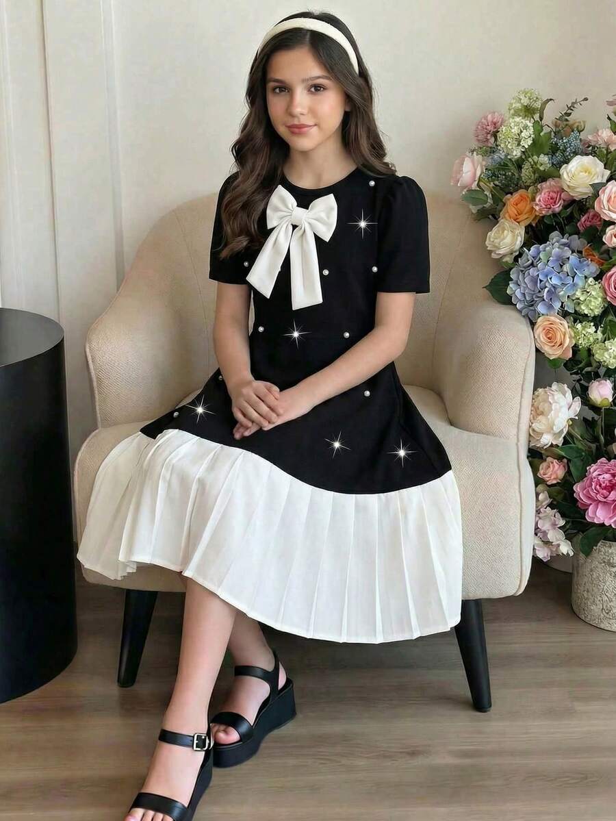 Tween girls apricot short-sleeve pleated smock dress with 3D bow decor and round neckline.