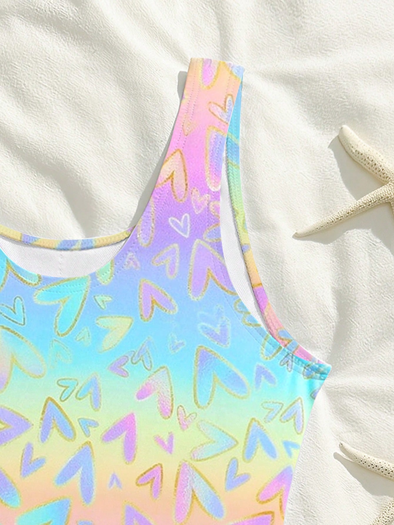 Tween girls one-piece swimsuit with a black base and multicolor tropical plant print featuring bamboo, palm leaves, plumeria flowers, scoop neck, and wide straps.