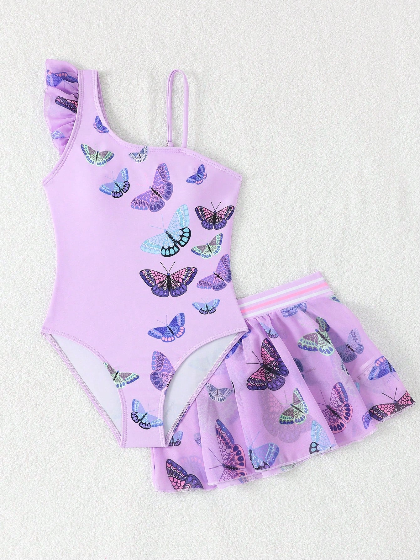 Girls yellow one-piece swimsuit with asymmetrical neckline, ruffle detail, sleeveless fitted style, and skirt bottom for beach and pool vacations.