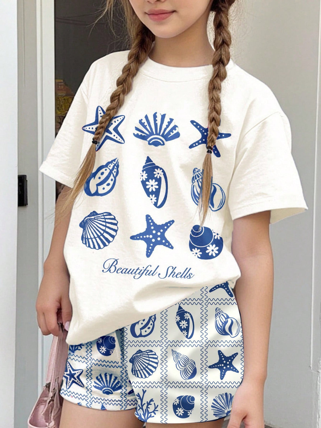 Tween girls 2-piece summer casual outfit featuring a multicolor seashell print short sleeve T-shirt with drop shoulders and matching loose fit shorts with pockets.