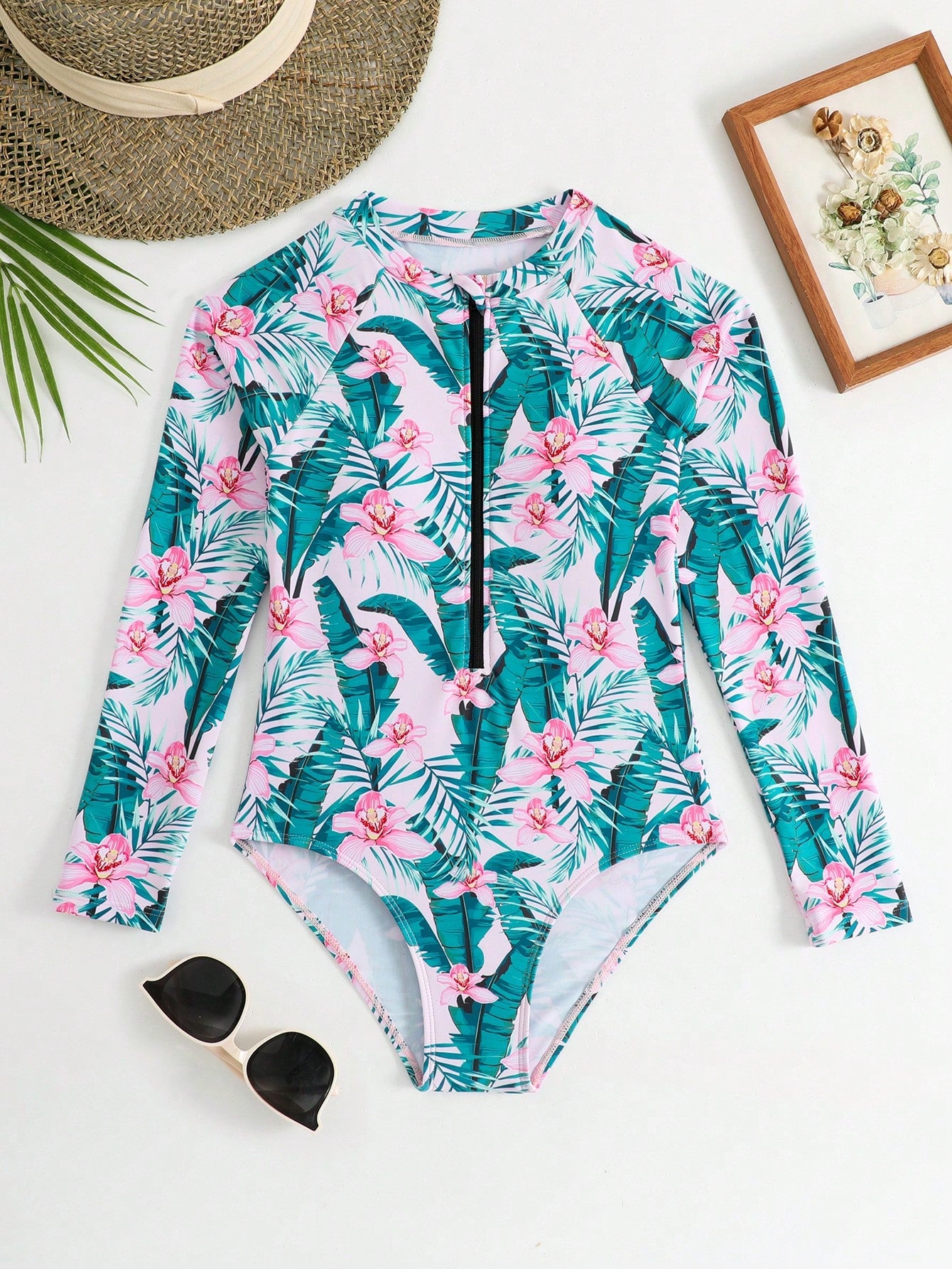 Girls one-piece swimsuit in blue with all-over leopard leaf print, ruffle detail, zipper front, high neck, and lined body for swimming and vacation.