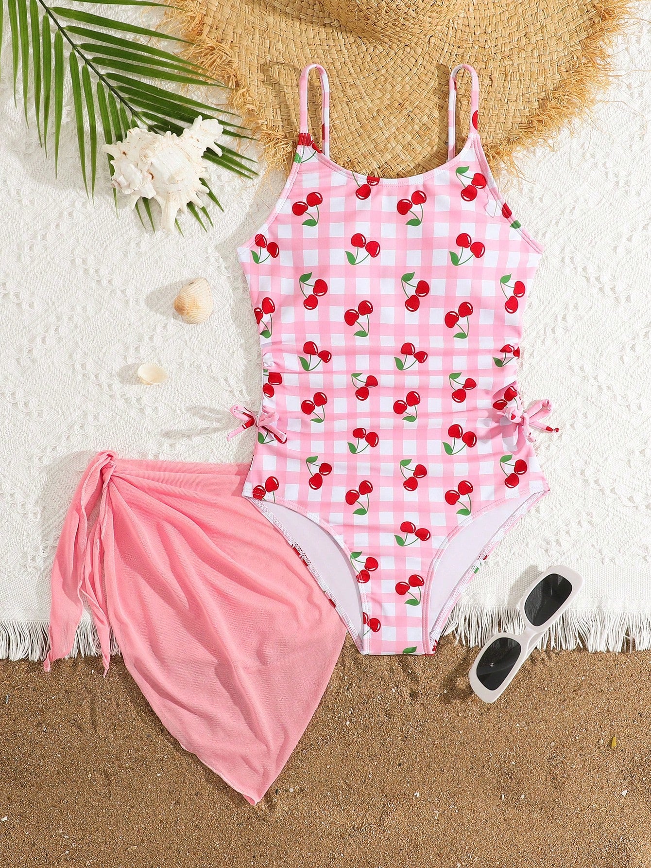 Tween girls 2-piece swimsuit in black with pink floral print, featuring spaghetti straps, bow decor, mesh detail, and a skirted mid-waist bottom. Sleeveless vacation-style swim set with medium-stretch fabric.