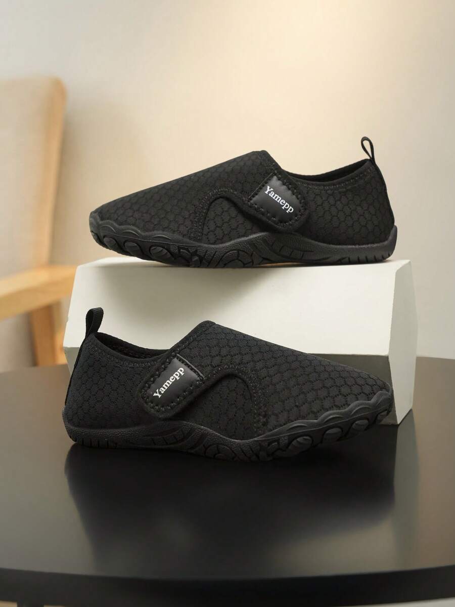 Black low-top kids water shoes featuring a breathable fabric upper, hook and loop closure, and rubber outsole for boys and girls.