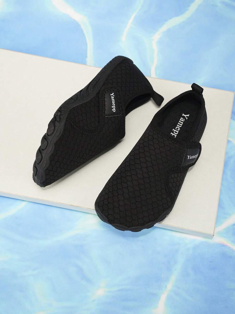 Black low-top kids water shoes featuring a breathable fabric upper, hook and loop closure, and rubber outsole for boys and girls.