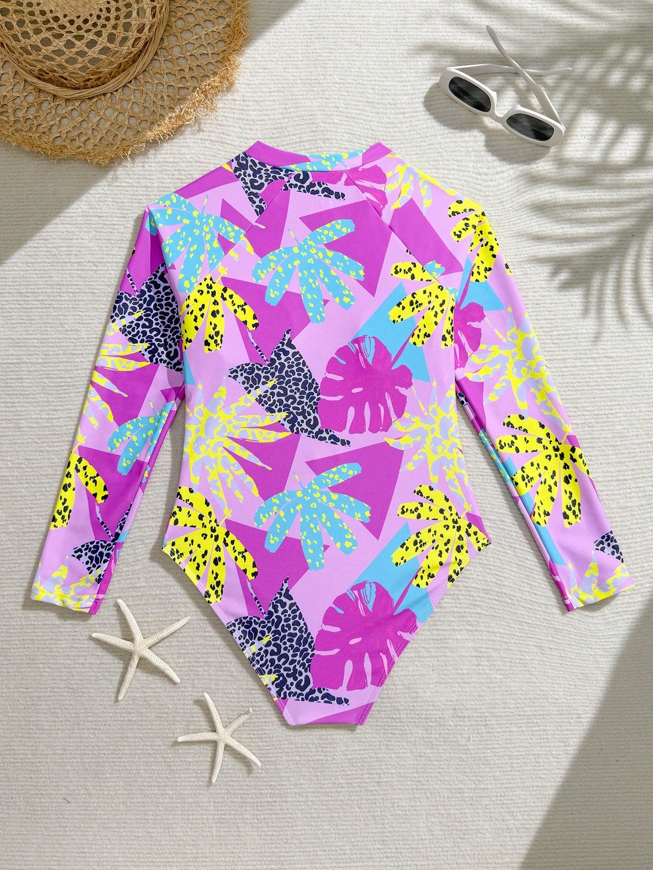 Girls one-piece swimsuit in blue with all-over leopard leaf print, ruffle detail, zipper front, high neck, and lined body for swimming and vacation.