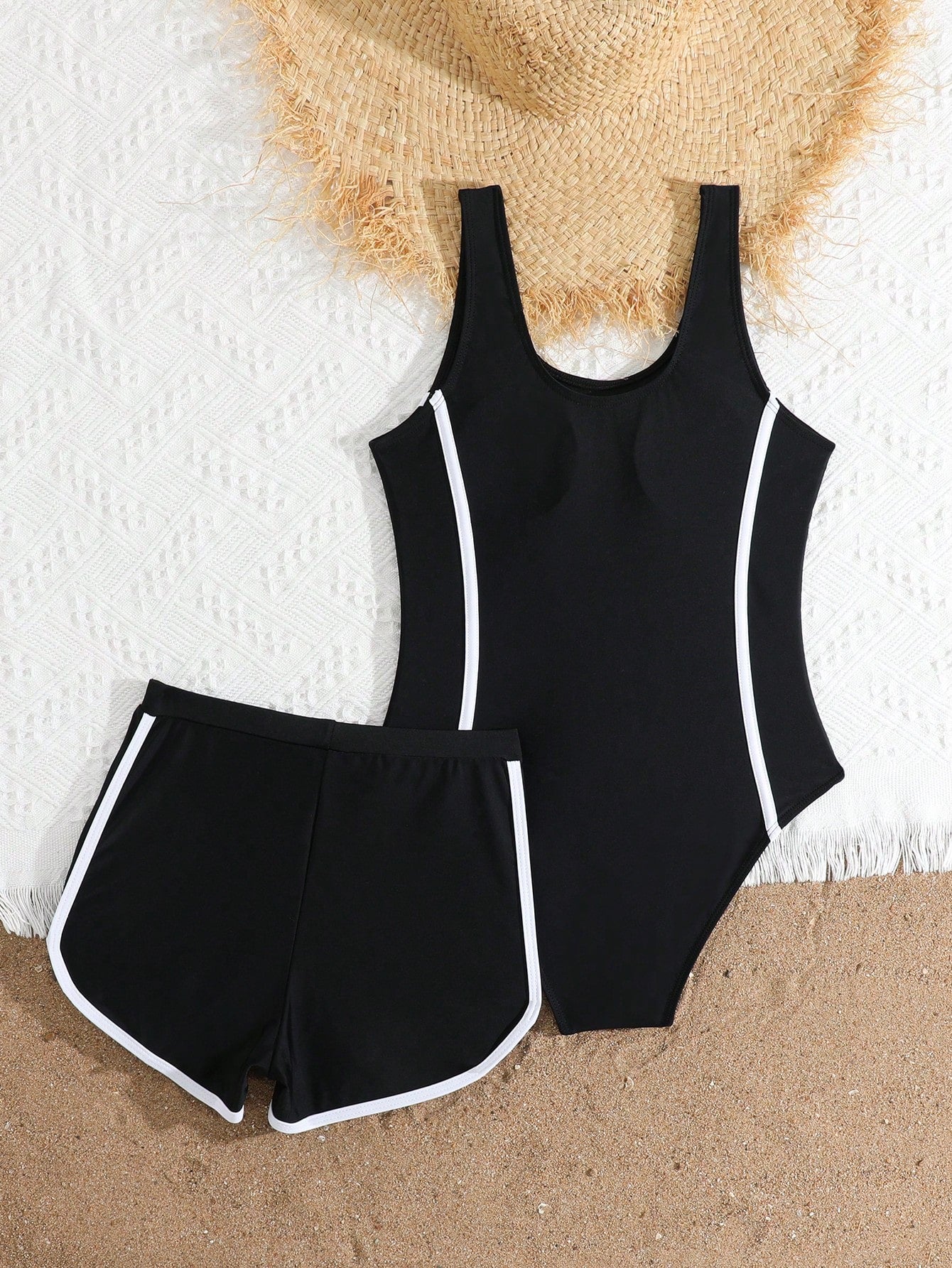 Tween girls 2-piece swimsuit set in black with full floral and plant print, featuring a sleeveless scoop-neck swim top and matching shorts-style bottoms.