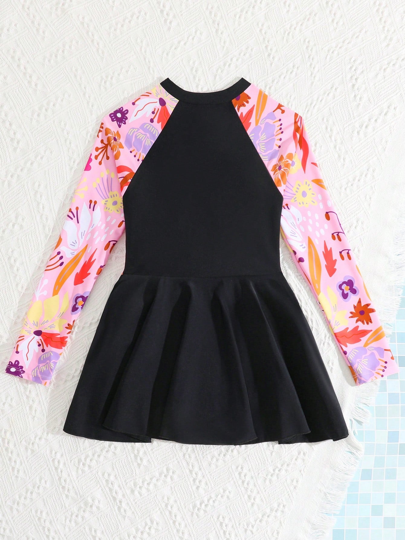 Tween girls one-piece swimsuit in black floral pattern with long sleeves, high neck, front zipper, and a skirt-style bottom.