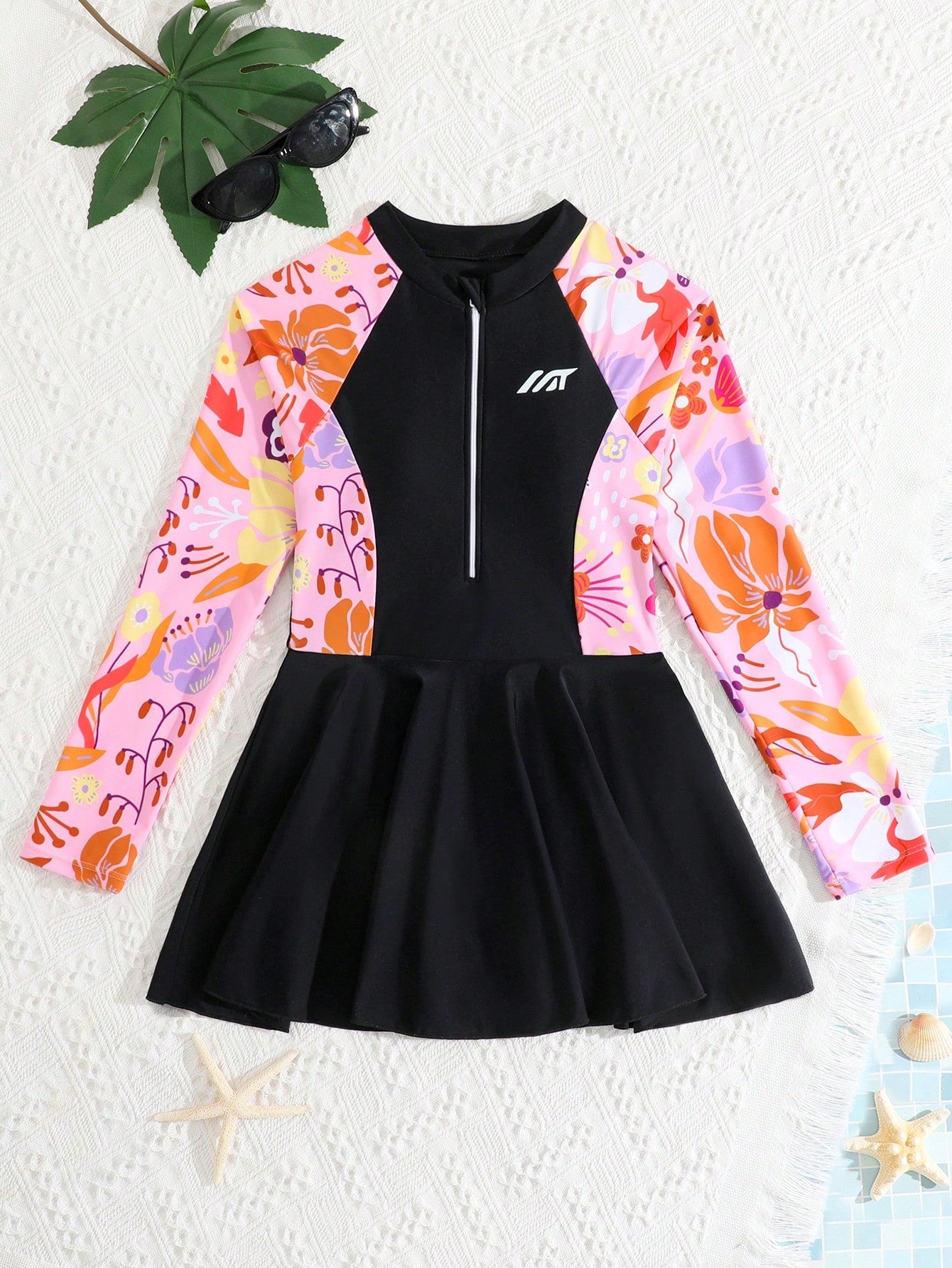Tween girls one-piece swimsuit in black floral pattern with long sleeves, high neck, front zipper, and a skirt-style bottom.