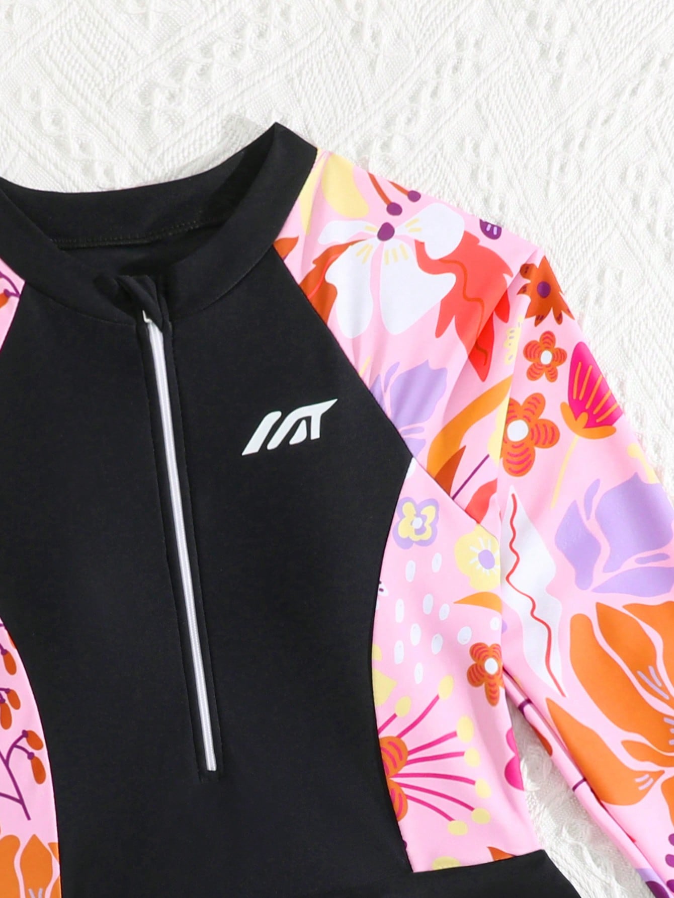 Tween girls one-piece swimsuit in black floral pattern with long sleeves, high neck, front zipper, and a skirt-style bottom.