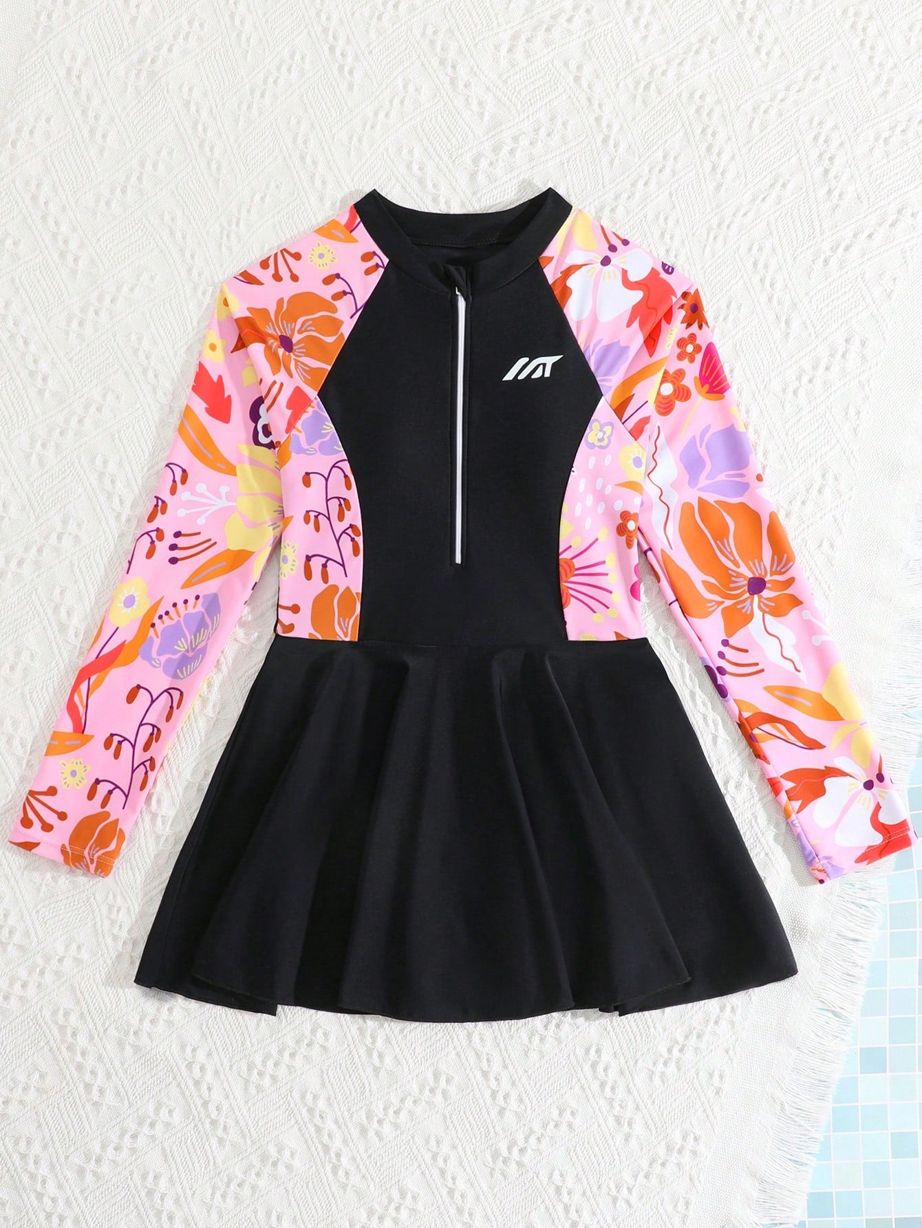 Tween girls one-piece swimsuit in black floral pattern with long sleeves, high neck, front zipper, and a skirt-style bottom.