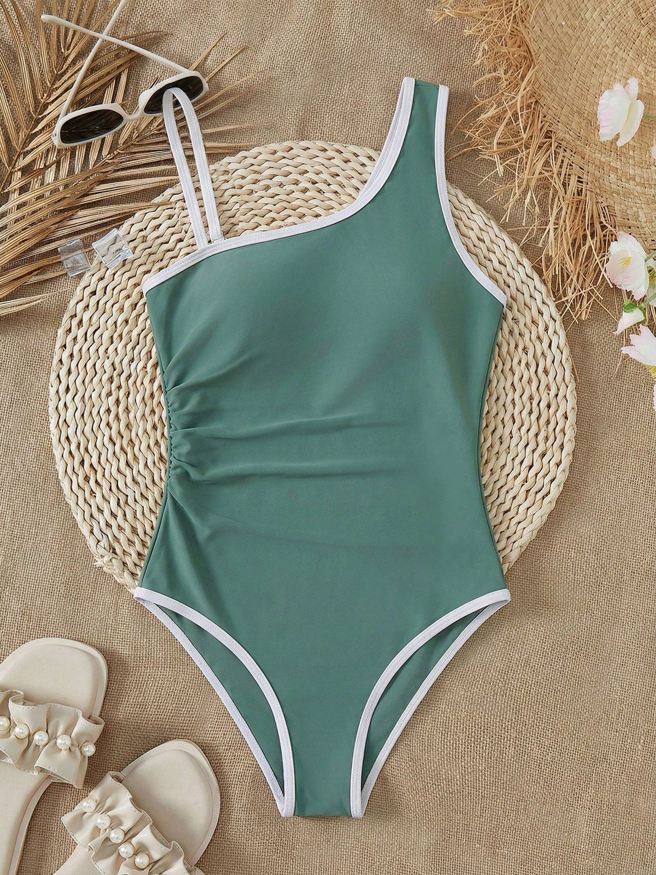 Tween girl one-piece swimsuit in brown polka dot geometric print with asymmetrical neckline, ruffle detail, cut-out design, and fitted mid-waist swim bottom.