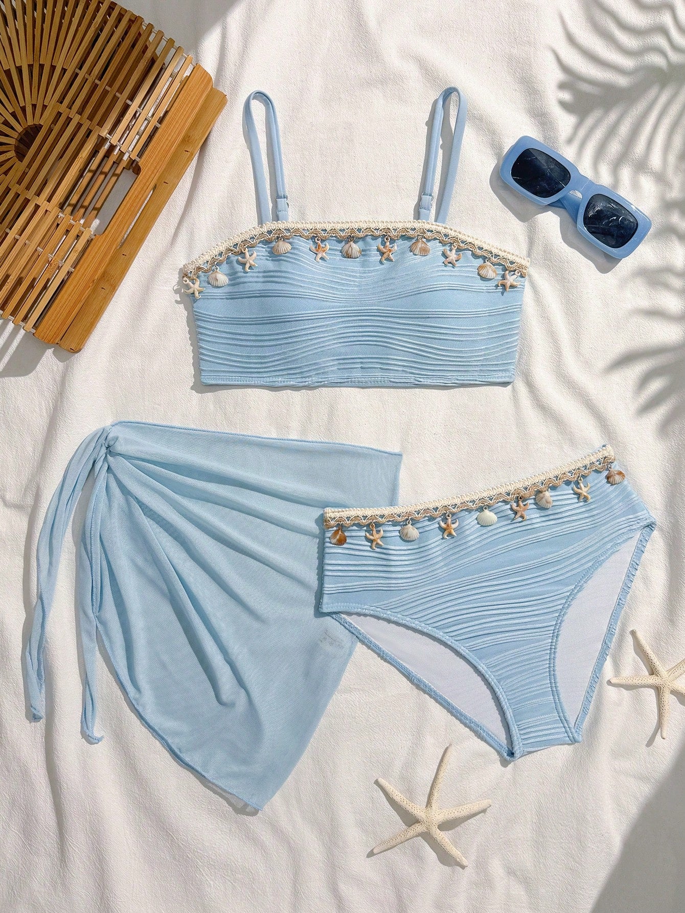 Tween girls bikini set with shell and starfish woven band details, spaghetti strap sleeveless top, and mid-waist skirt-style bottom in blue.