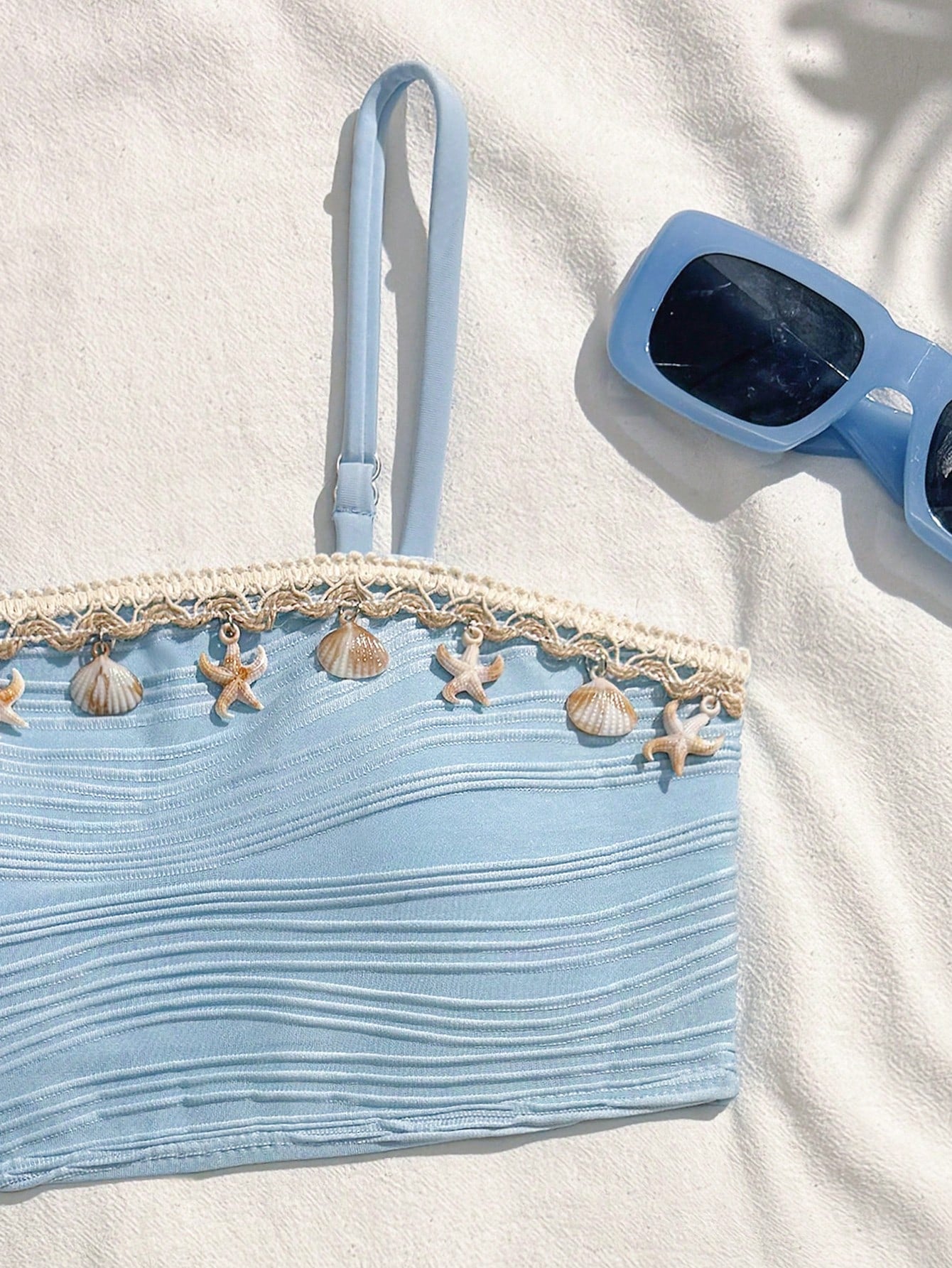 Tween girls bikini set with shell and starfish woven band details, spaghetti strap sleeveless top, and mid-waist skirt-style bottom in blue.
