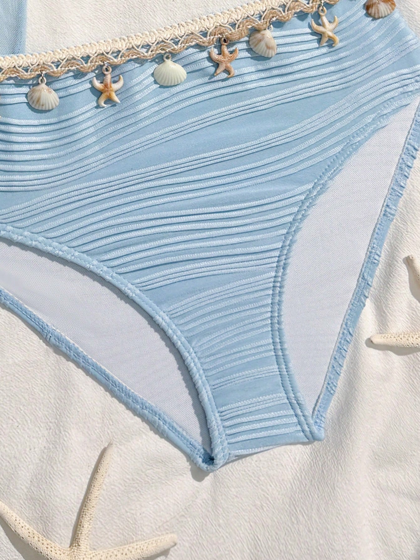 Tween girls bikini set with shell and starfish woven band details, spaghetti strap sleeveless top, and mid-waist skirt-style bottom in blue.