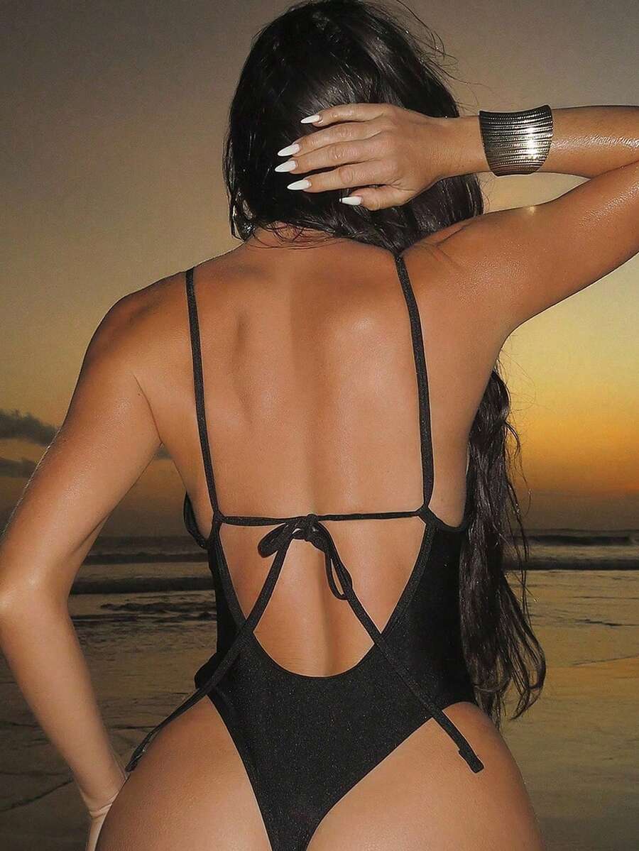 Women's black lace one-piece swimsuit featuring a deep V-neckline, spaghetti straps, backless tie-up detail, and thong bottom.