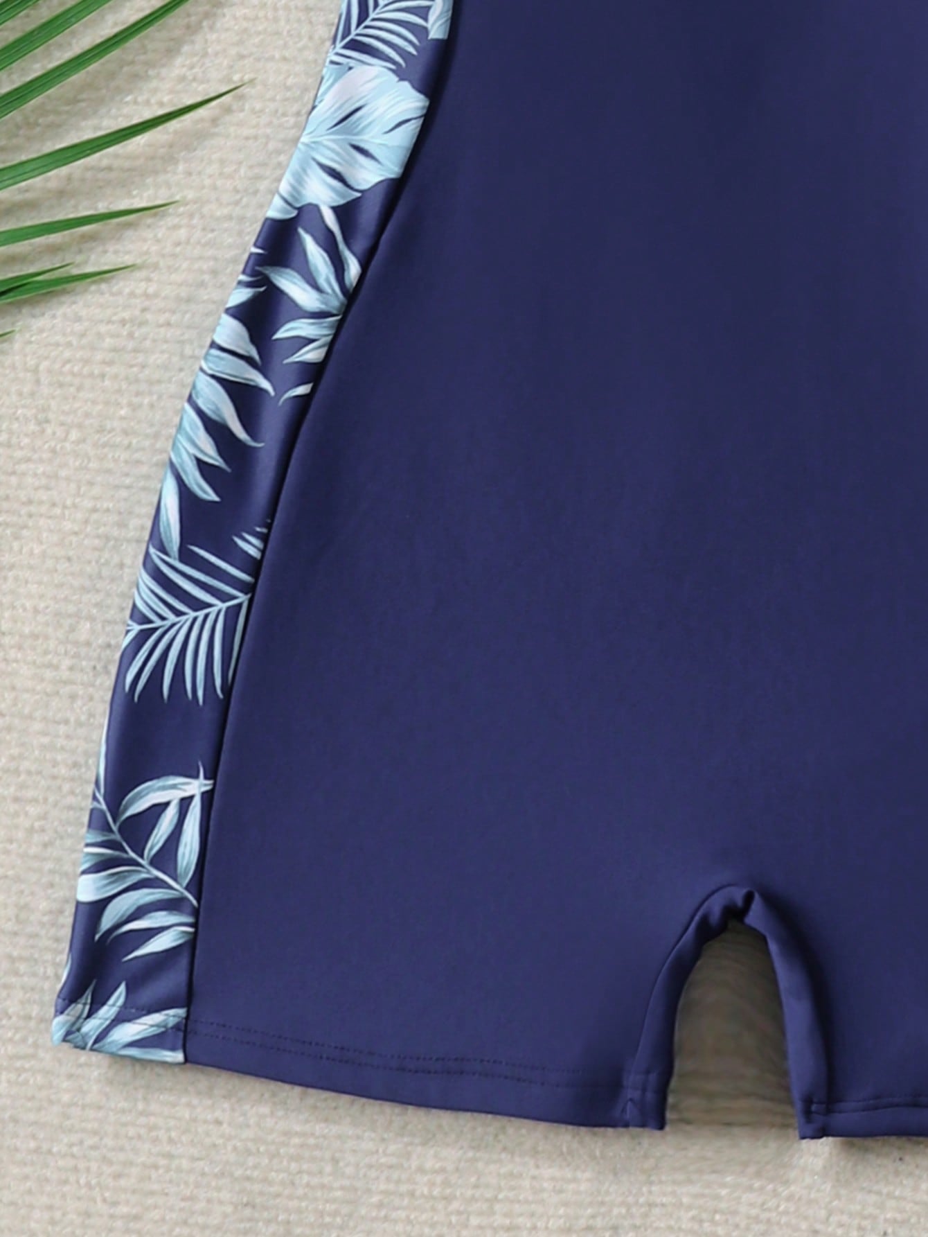 Black and white one-piece rashguard swimsuit for tween girls with short sleeves, high neck, zipper detail, fitted shape, and shorts-style bottom.