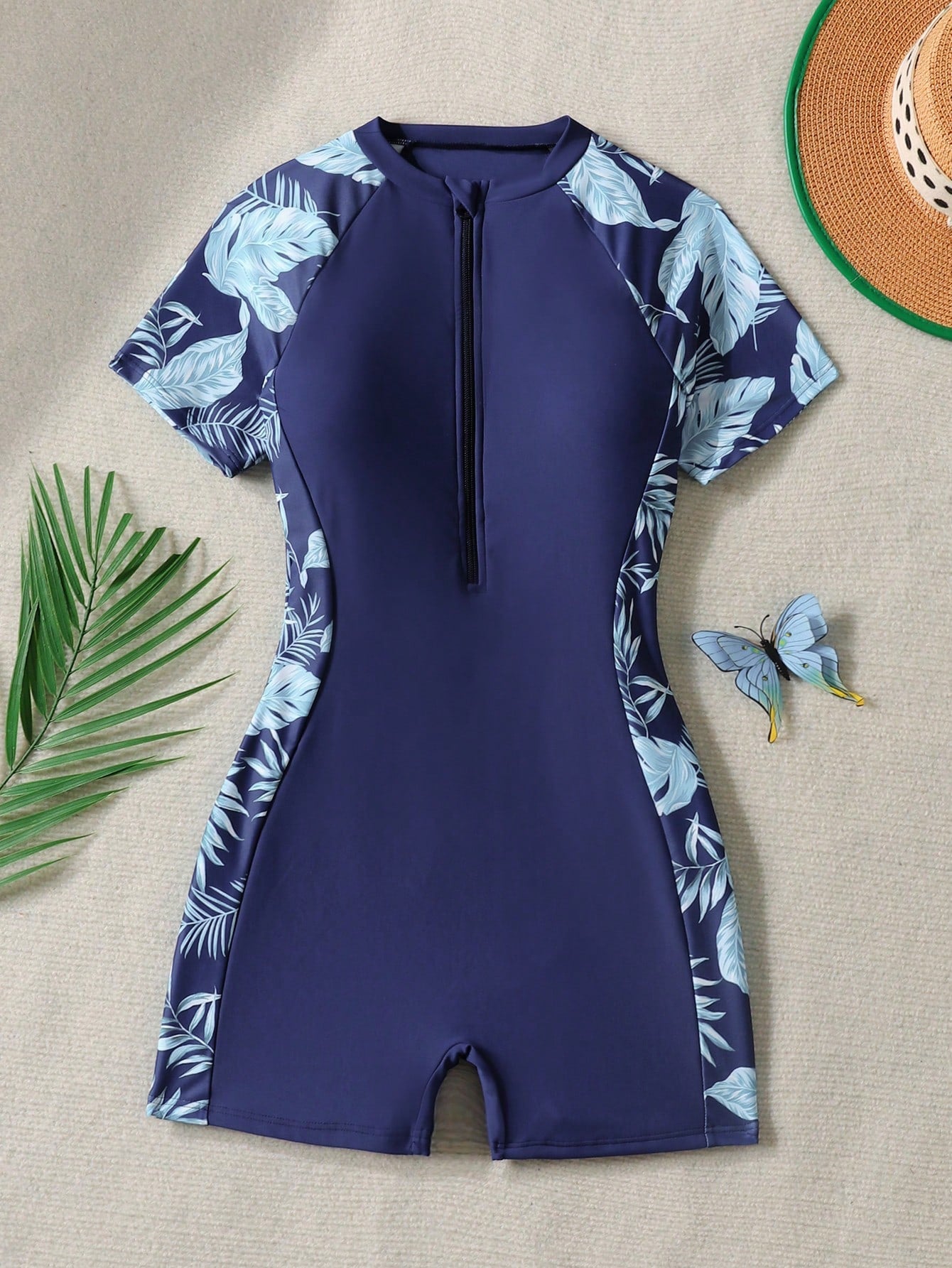 Black and white one-piece rashguard swimsuit for tween girls with short sleeves, high neck, zipper detail, fitted shape, and shorts-style bottom.