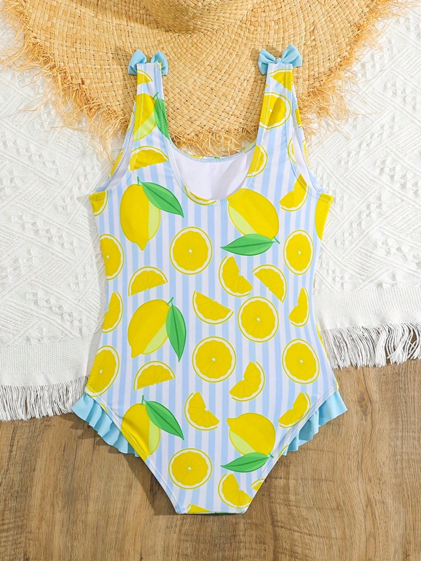 Tween girls purple one-piece swimsuit with lemon stripe pattern, spaghetti straps, ruffle detail, bow design, scoop neckline, and fitted swimwear shape
