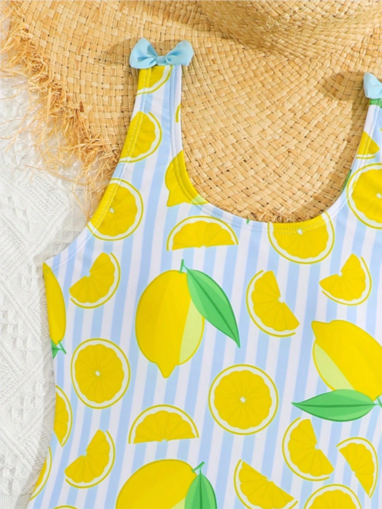 Tween girls purple one-piece swimsuit with lemon stripe pattern, spaghetti straps, ruffle detail, bow design, scoop neckline, and fitted swimwear shape