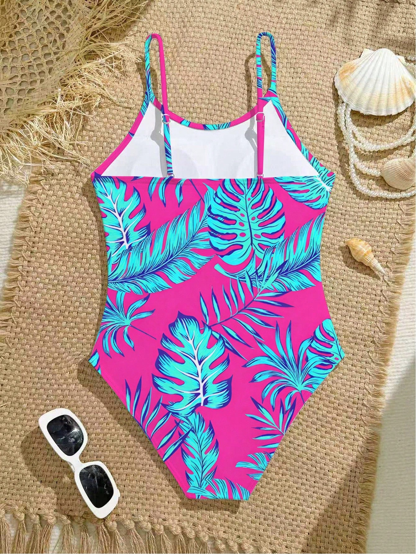 Tween girls one-piece swimsuit with a floral plant print, spaghetti straps, and a mid-waist fit in black.