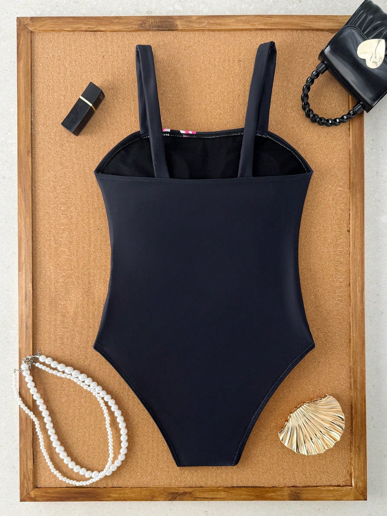 Tween girls one-piece swimsuit with a floral plant print, spaghetti straps, and a mid-waist fit in black.