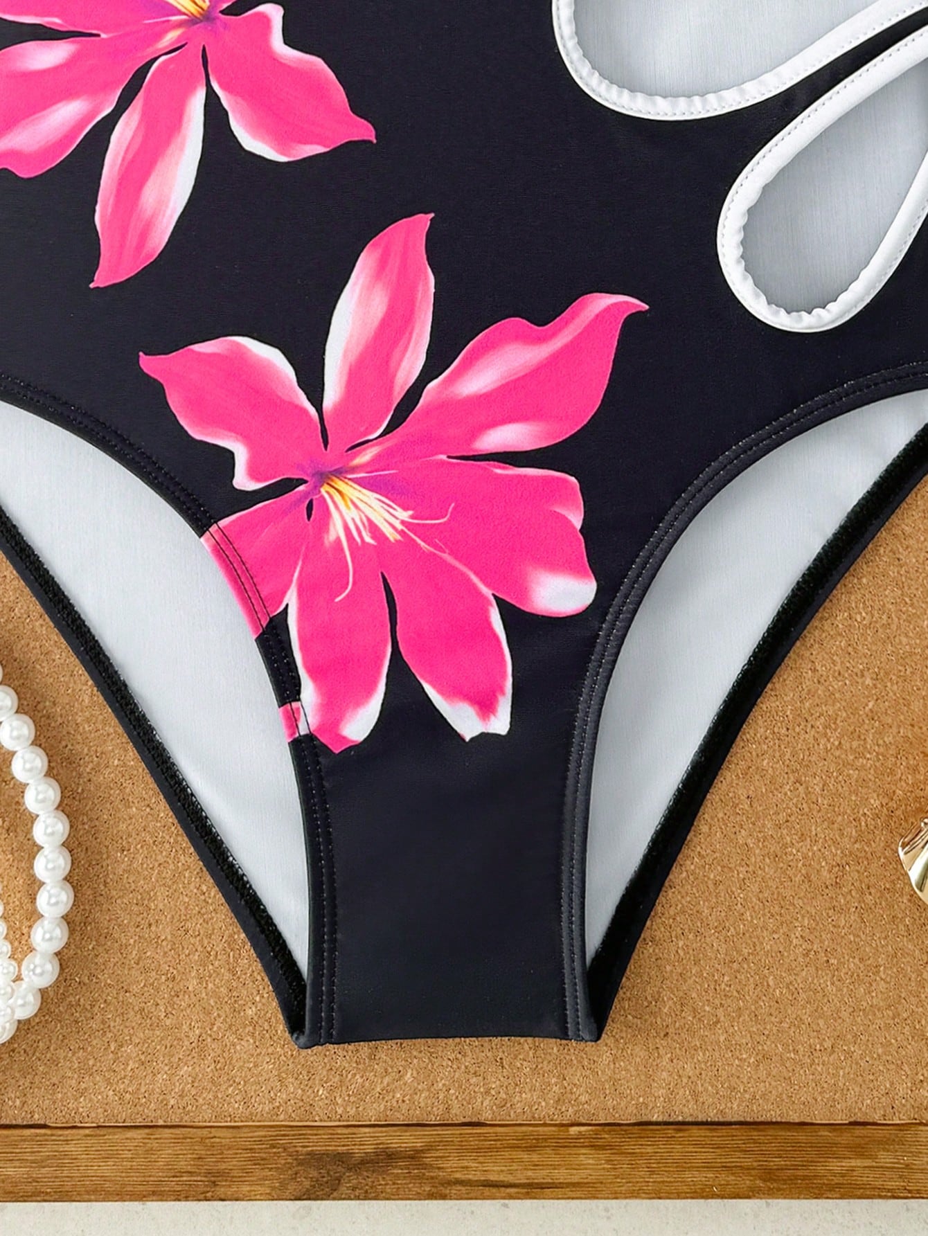 Tween girls one-piece swimsuit with a floral plant print, spaghetti straps, and a mid-waist fit in black.