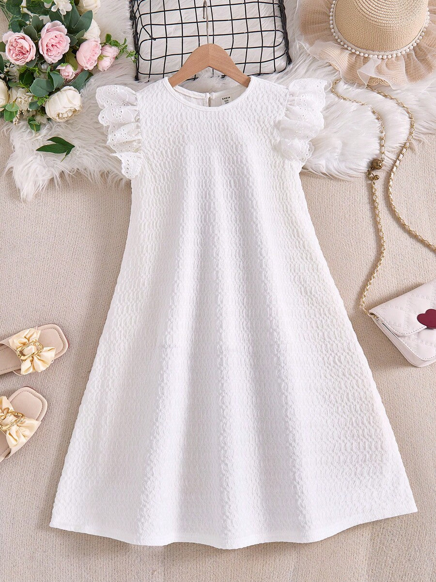 Tween girl wearing a sleeveless black tunic dress featuring a round neck, contrast lace details, and a straight hem.