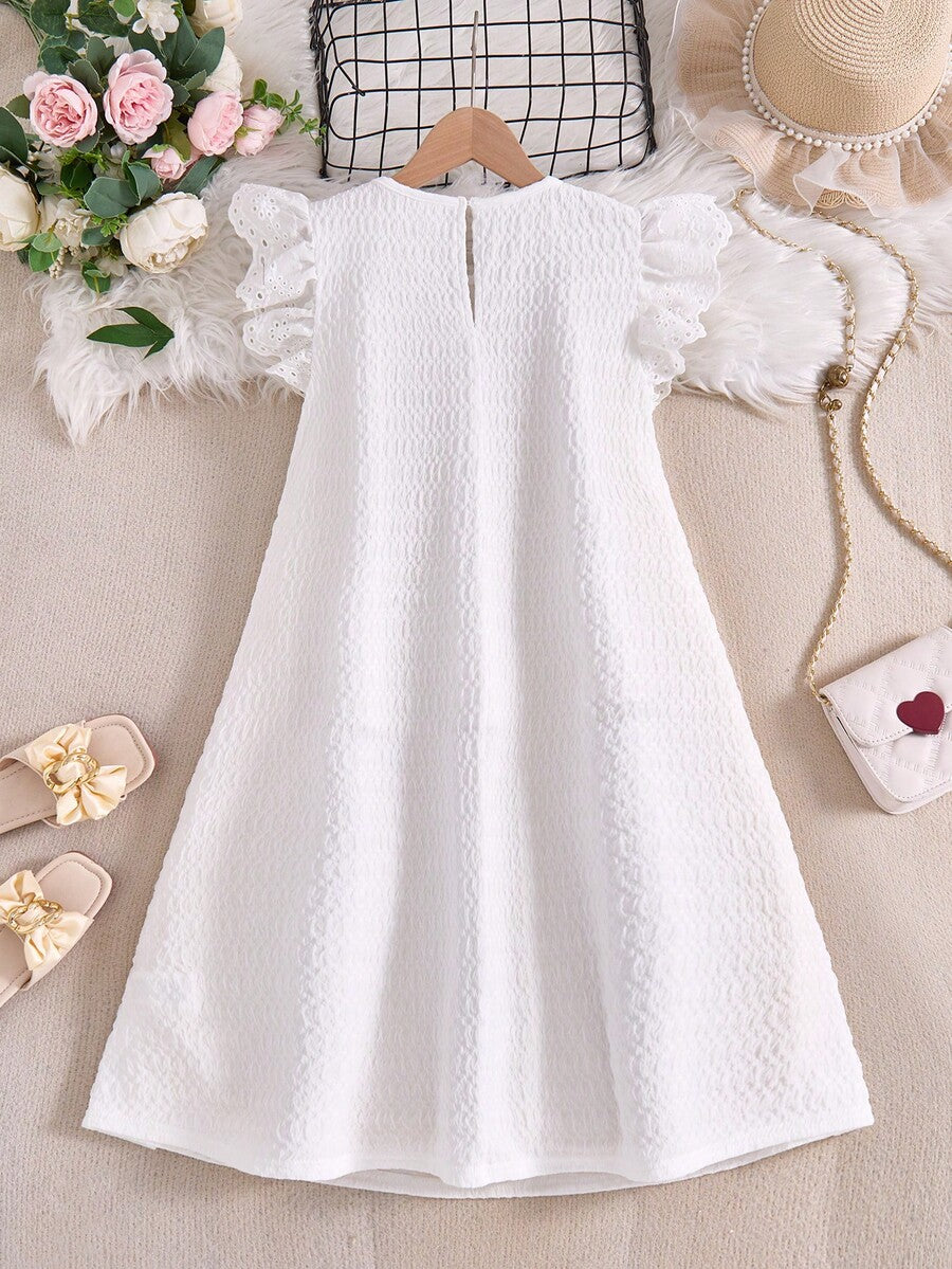 Tween girl wearing a sleeveless black tunic dress featuring a round neck, contrast lace details, and a straight hem.