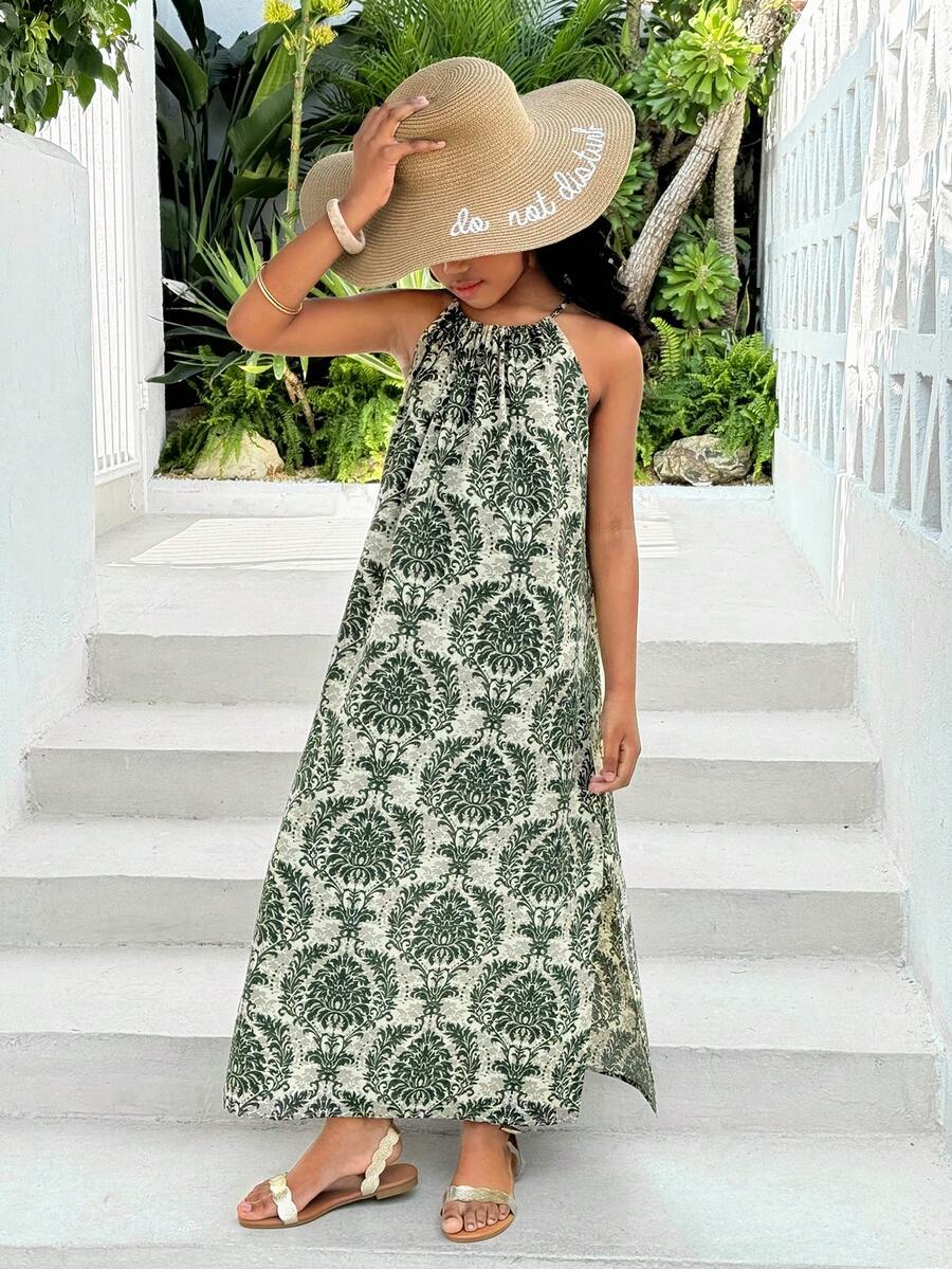 Tween girls green floral print cami dress with halter neckline, sleeveless cut, zipper detail, flared hem, and long vacation style silhouette.