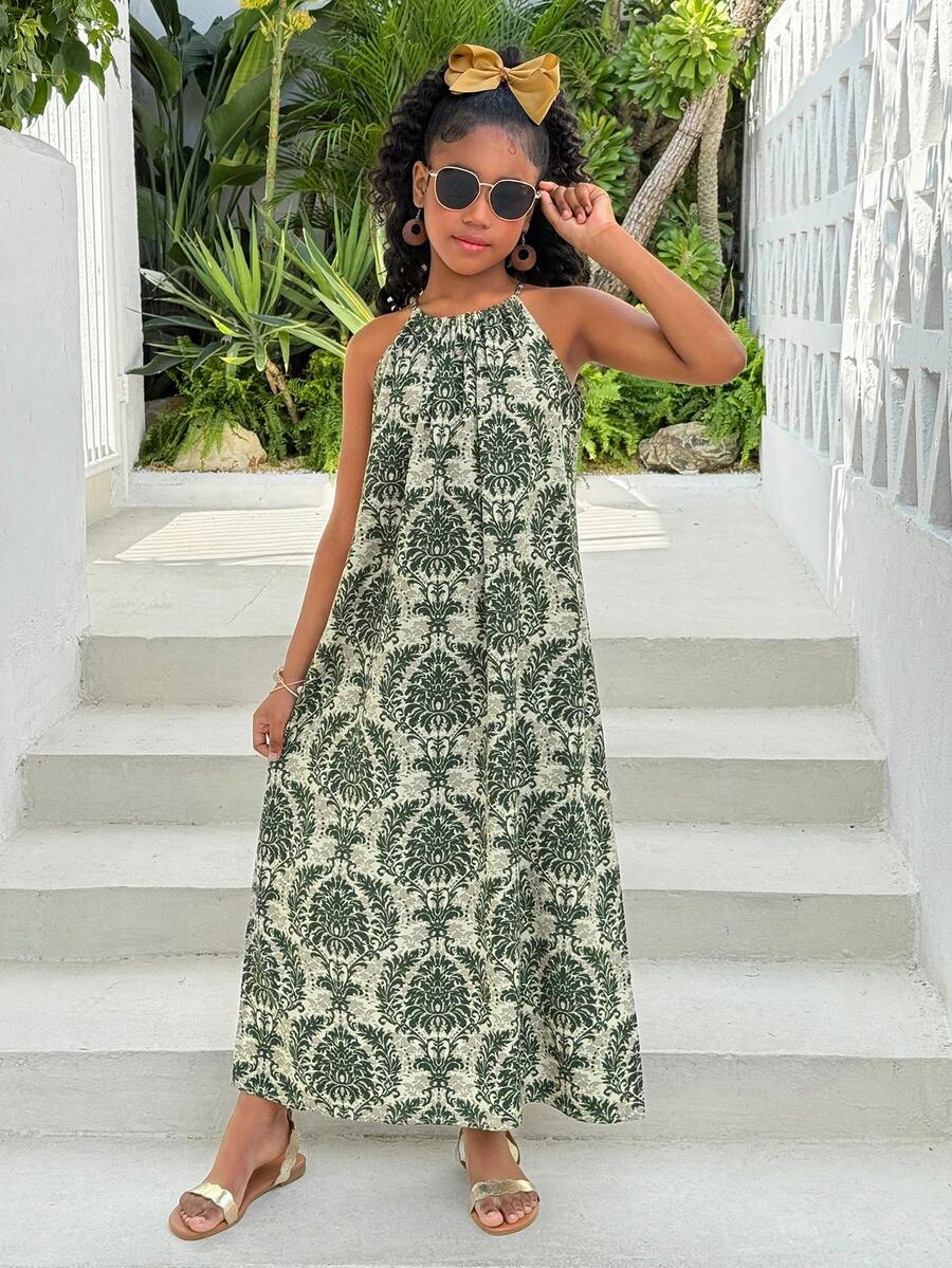 Tween girls green floral print cami dress with halter neckline, sleeveless cut, zipper detail, flared hem, and long vacation style silhouette.
