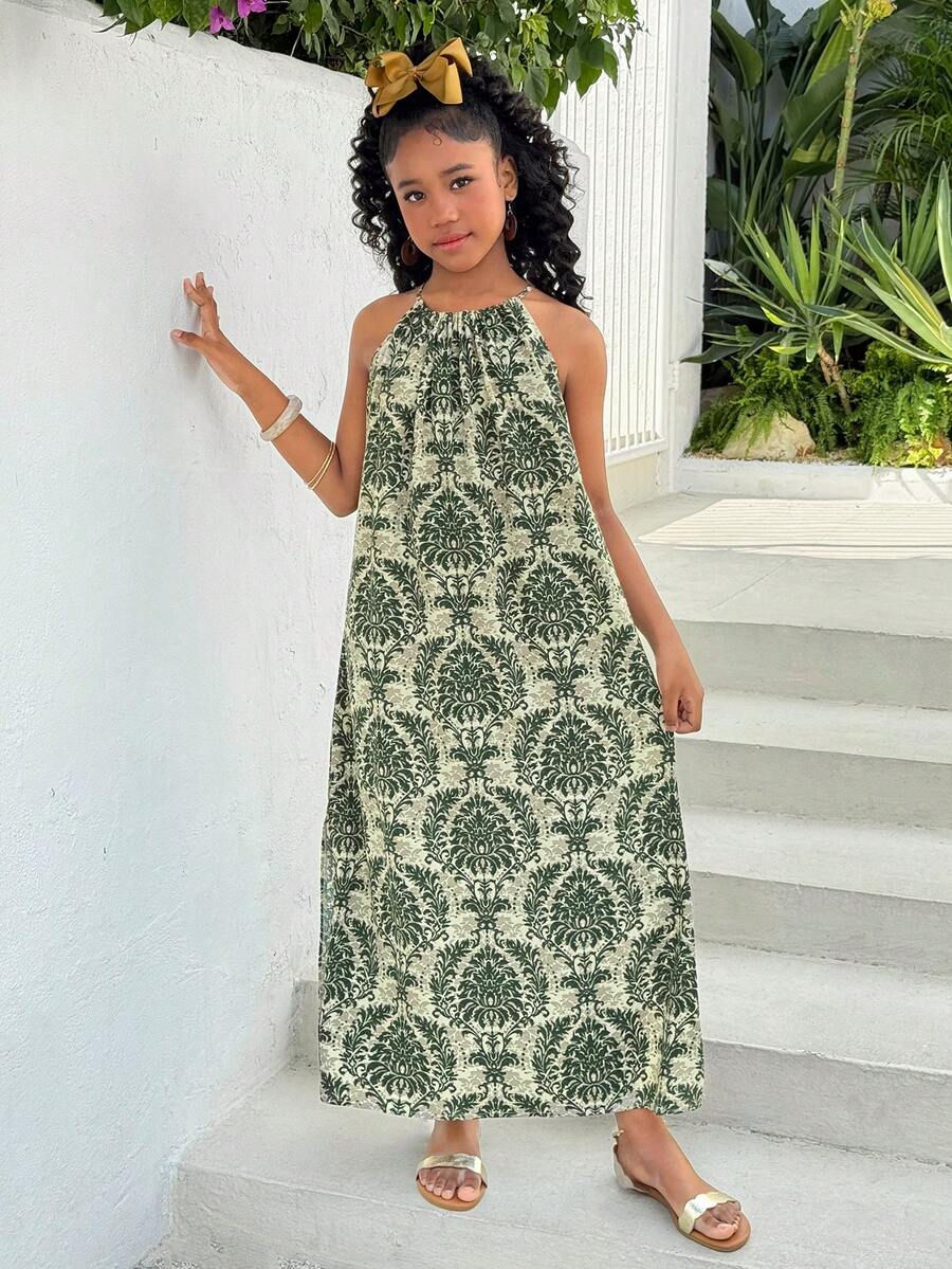 Tween girls green floral print cami dress with halter neckline, sleeveless cut, zipper detail, flared hem, and long vacation style silhouette.