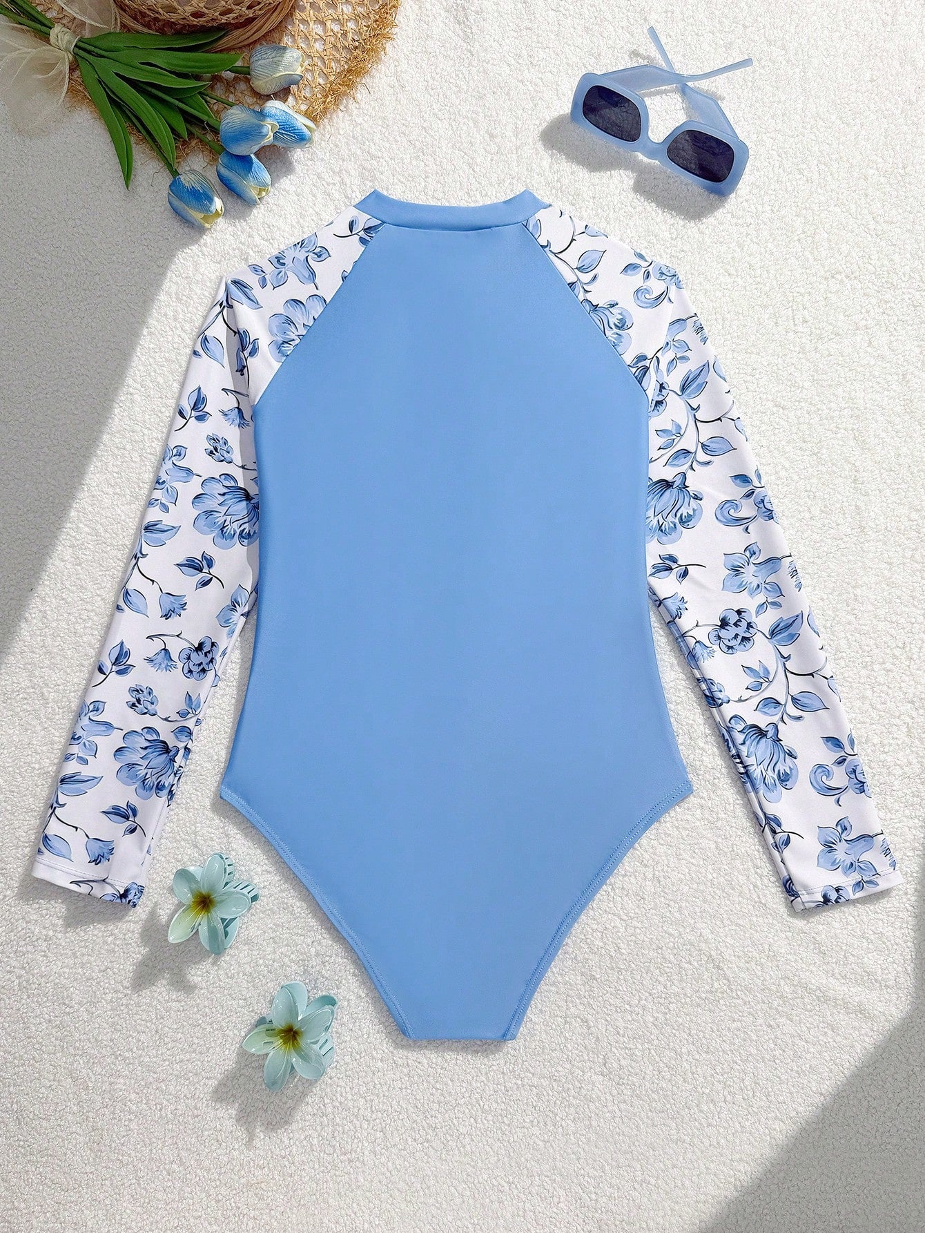 Girls one-piece swimsuit in blue with all-over leopard leaf print, ruffle detail, zipper front, high neck, and lined body for swimming and vacation.