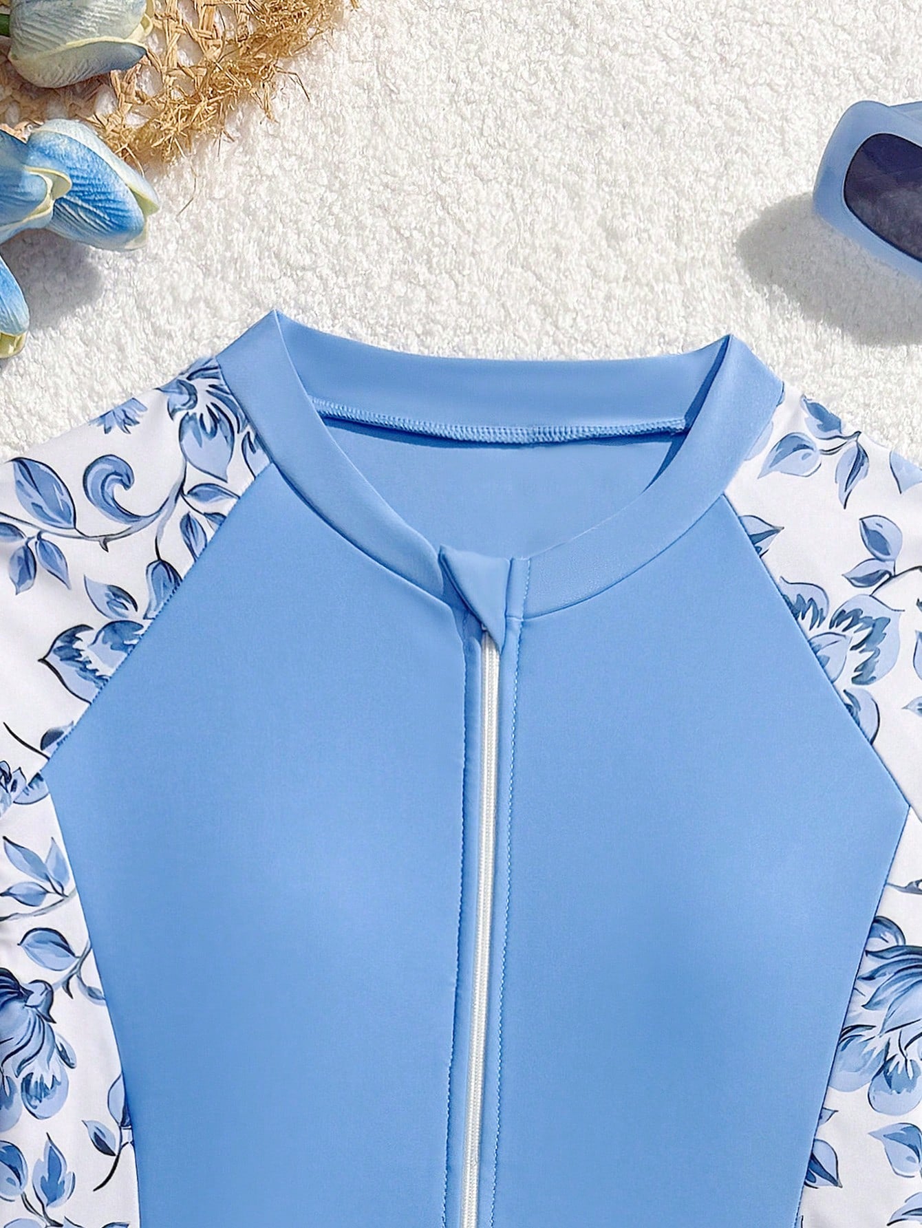 Girls one-piece swimsuit in blue with all-over leopard leaf print, ruffle detail, zipper front, high neck, and lined body for swimming and vacation.