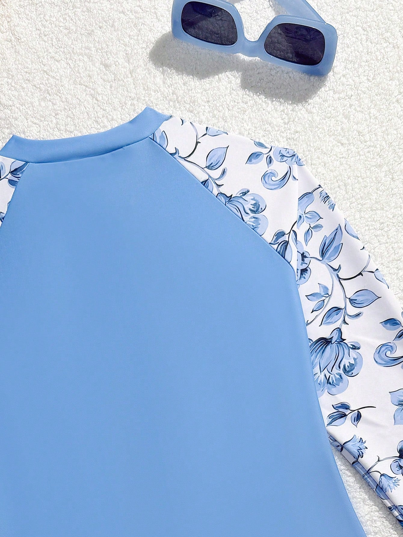 Girls one-piece swimsuit in blue with all-over leopard leaf print, ruffle detail, zipper front, high neck, and lined body for swimming and vacation.