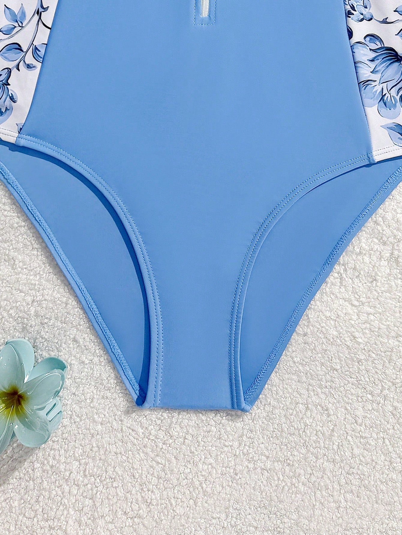 Girls one-piece swimsuit in blue with all-over leopard leaf print, ruffle detail, zipper front, high neck, and lined body for swimming and vacation.