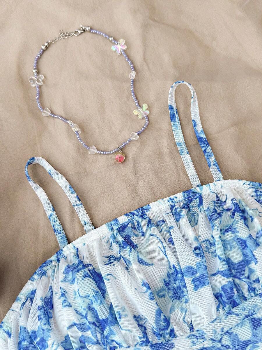 Tween girl yellow mini sundress with large pink floral hibiscus print, spaghetti straps, high waist, flared hem, and sleeveless cami style for summer beach wear