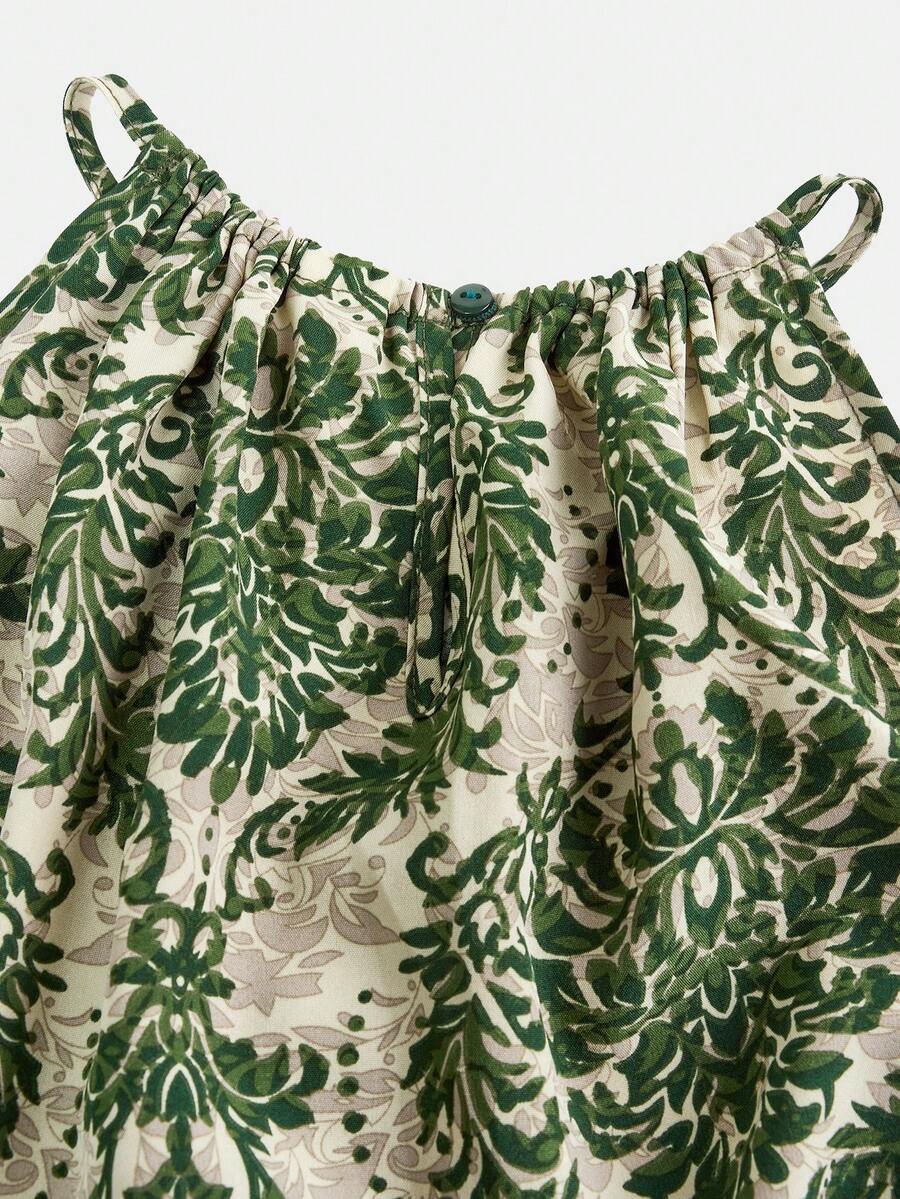 Tween girls green floral print cami dress with halter neckline, sleeveless cut, zipper detail, flared hem, and long vacation style silhouette.