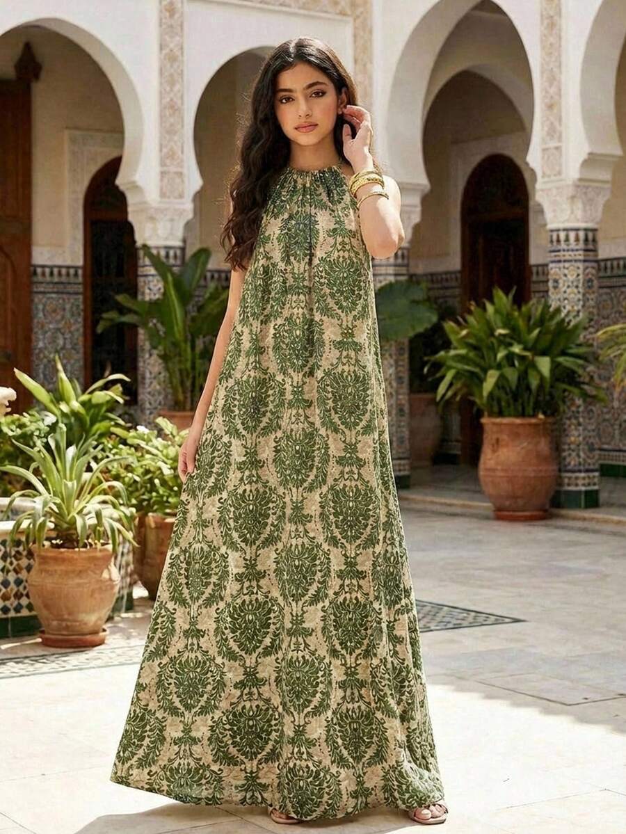 Tween girls green floral print cami dress with halter neckline, sleeveless cut, zipper detail, flared hem, and long vacation style silhouette.