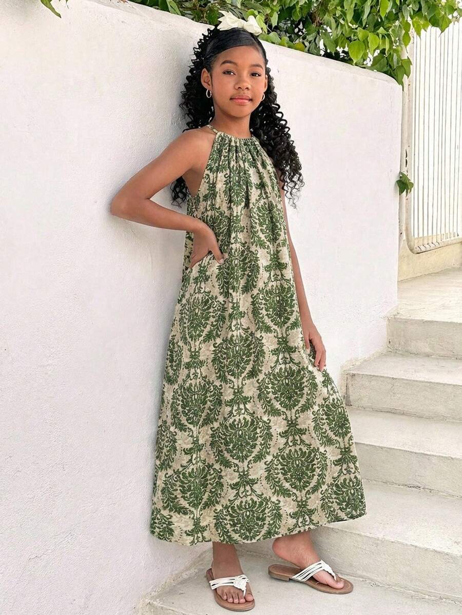 Tween girls green floral print cami dress with halter neckline, sleeveless cut, zipper detail, flared hem, and long vacation style silhouette.