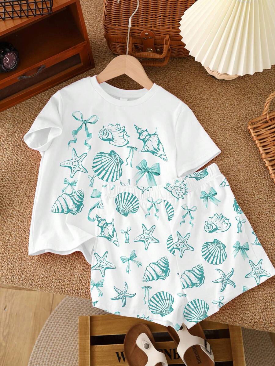 Teen girl wearing 2-piece summer vacation set with blue and white striped short sleeve top featuring seashell ocean bow print and matching loose fit shorts with pockets.