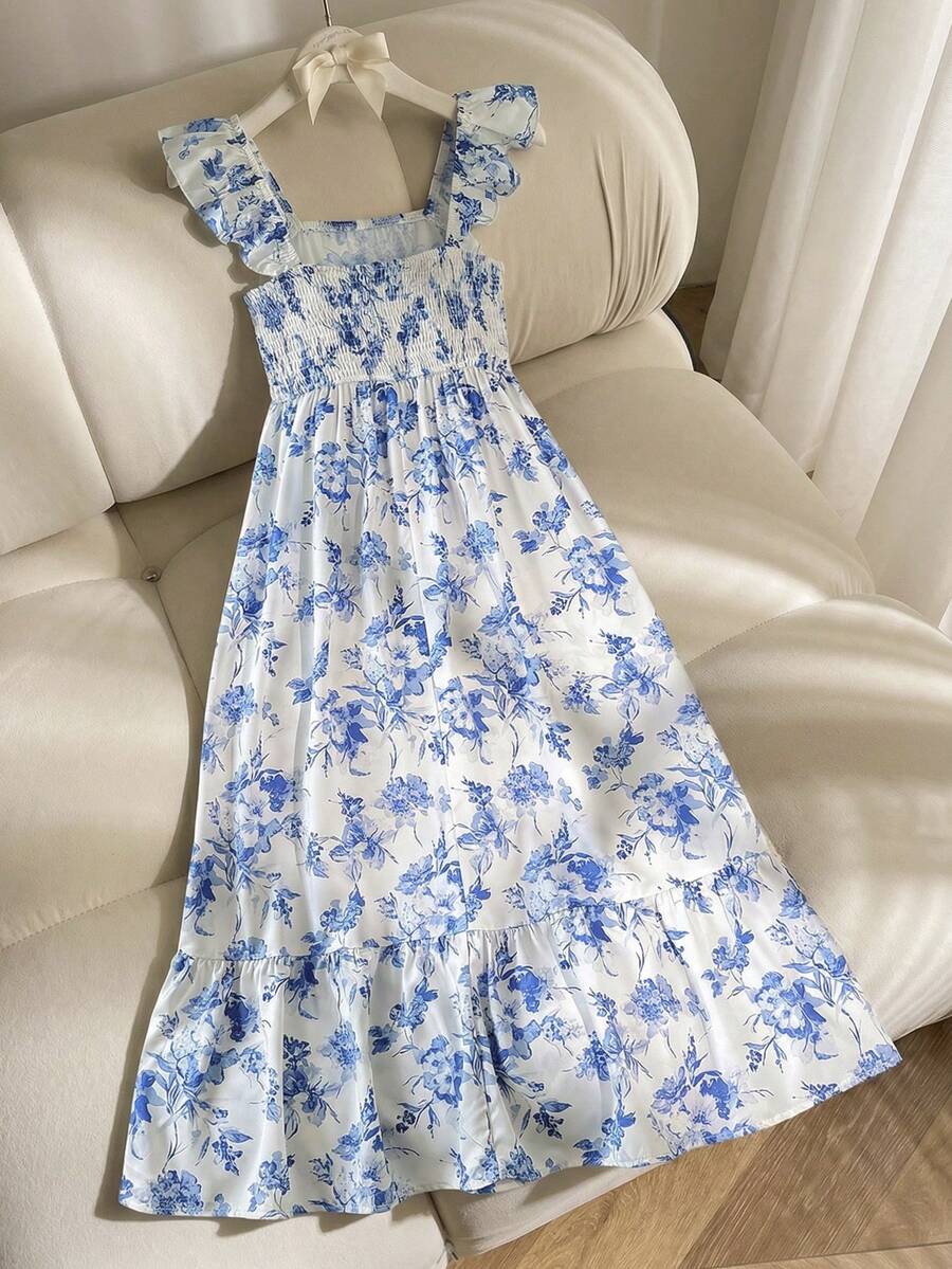 Blue floral print long vacation dress for tween girls featuring an A-line high waist silhouette with ruffle details and spaghetti straps.