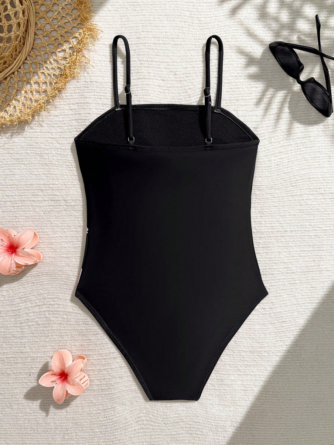 Tween girls one-piece swimsuit with a floral plant print, spaghetti straps, and a mid-waist fit in black.