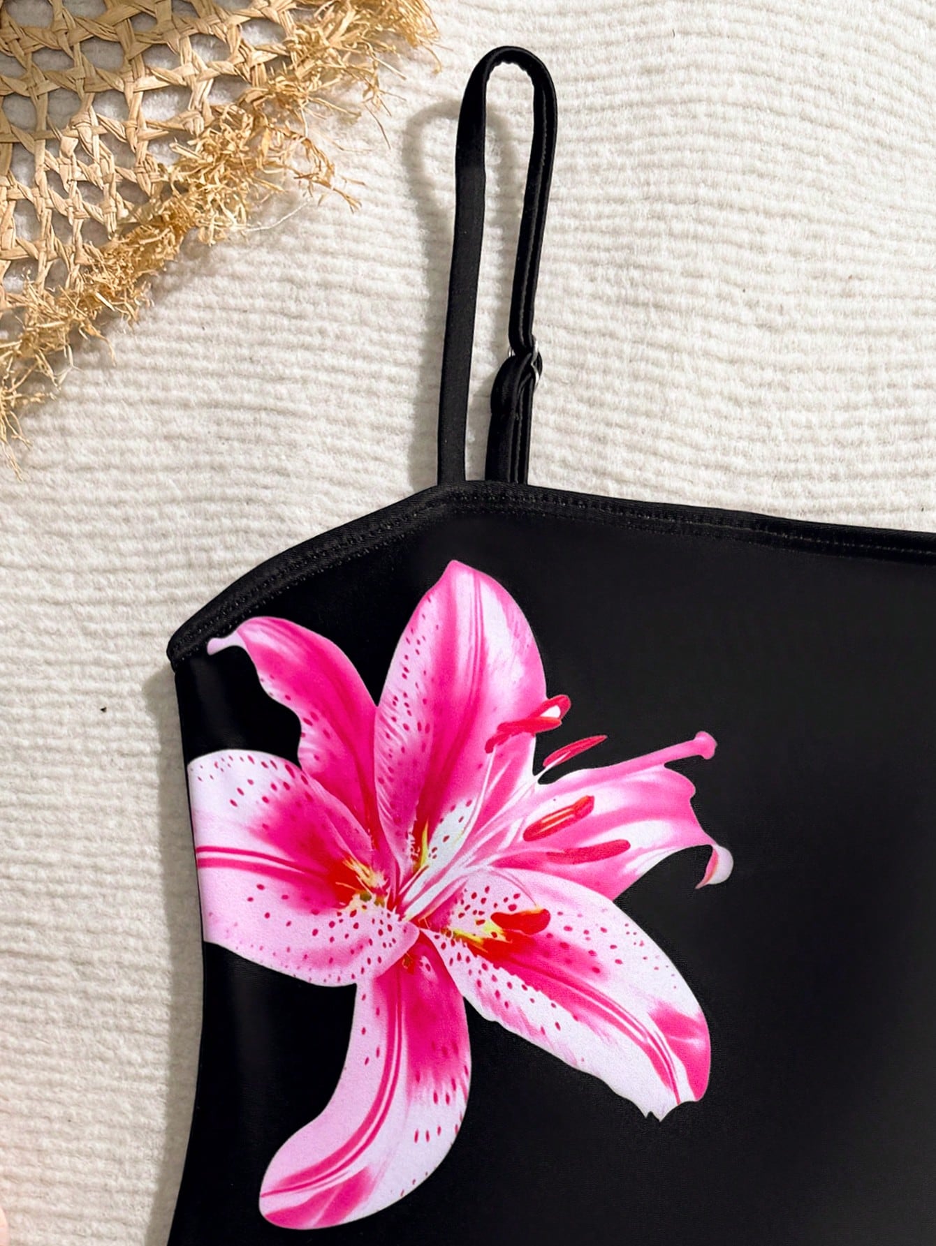 Tween girls one-piece swimsuit with a floral plant print, spaghetti straps, and a mid-waist fit in black.