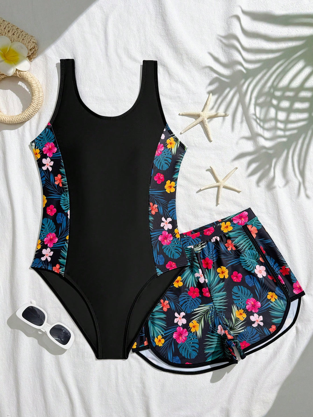Tween girls 2-piece swimsuit set in black with full floral and plant print, featuring a sleeveless scoop-neck swim top and matching shorts-style bottoms.