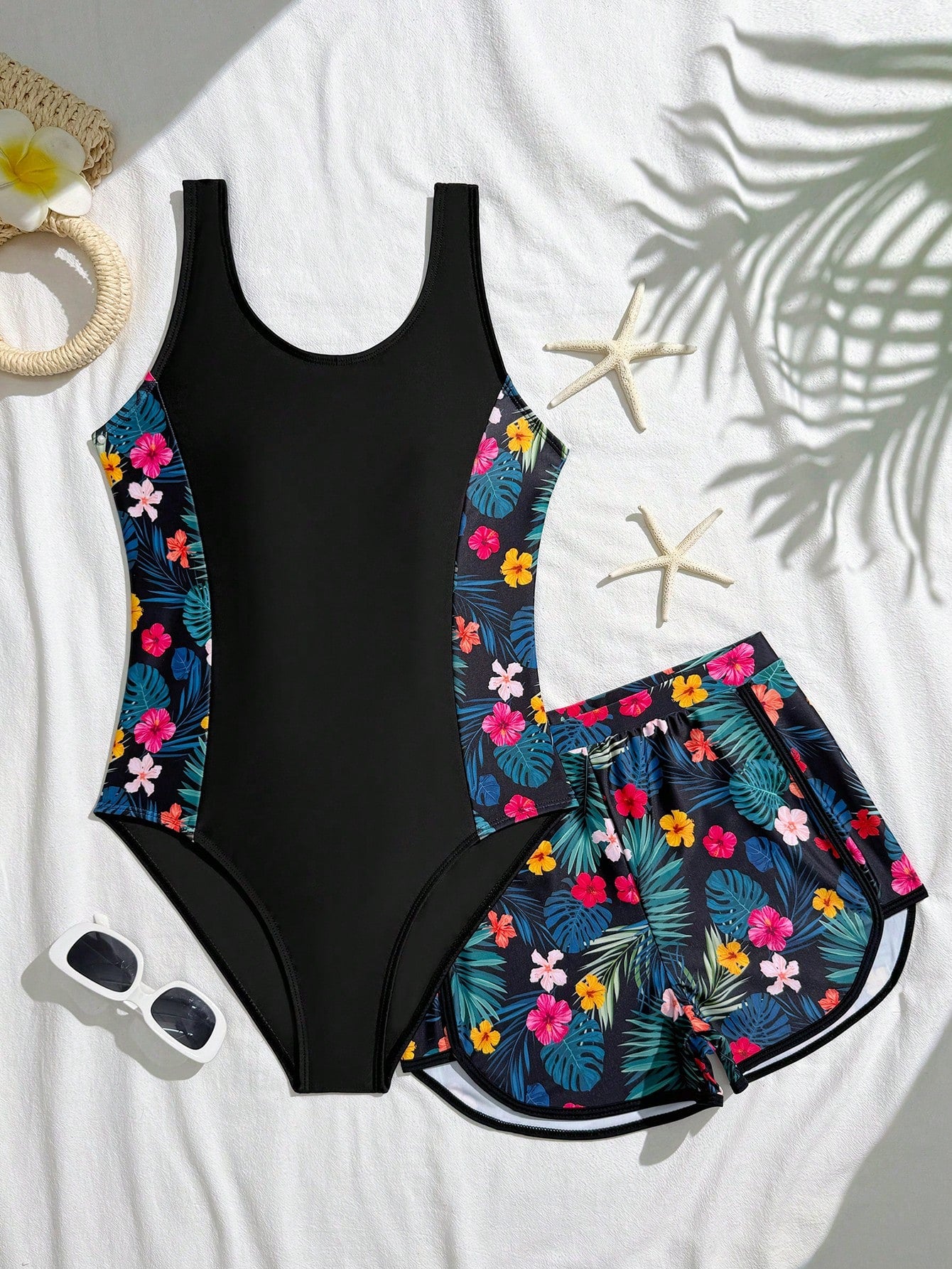 Tween girls 2-piece swimsuit set in black with full floral and plant print, featuring a sleeveless scoop-neck swim top and matching shorts-style bottoms.